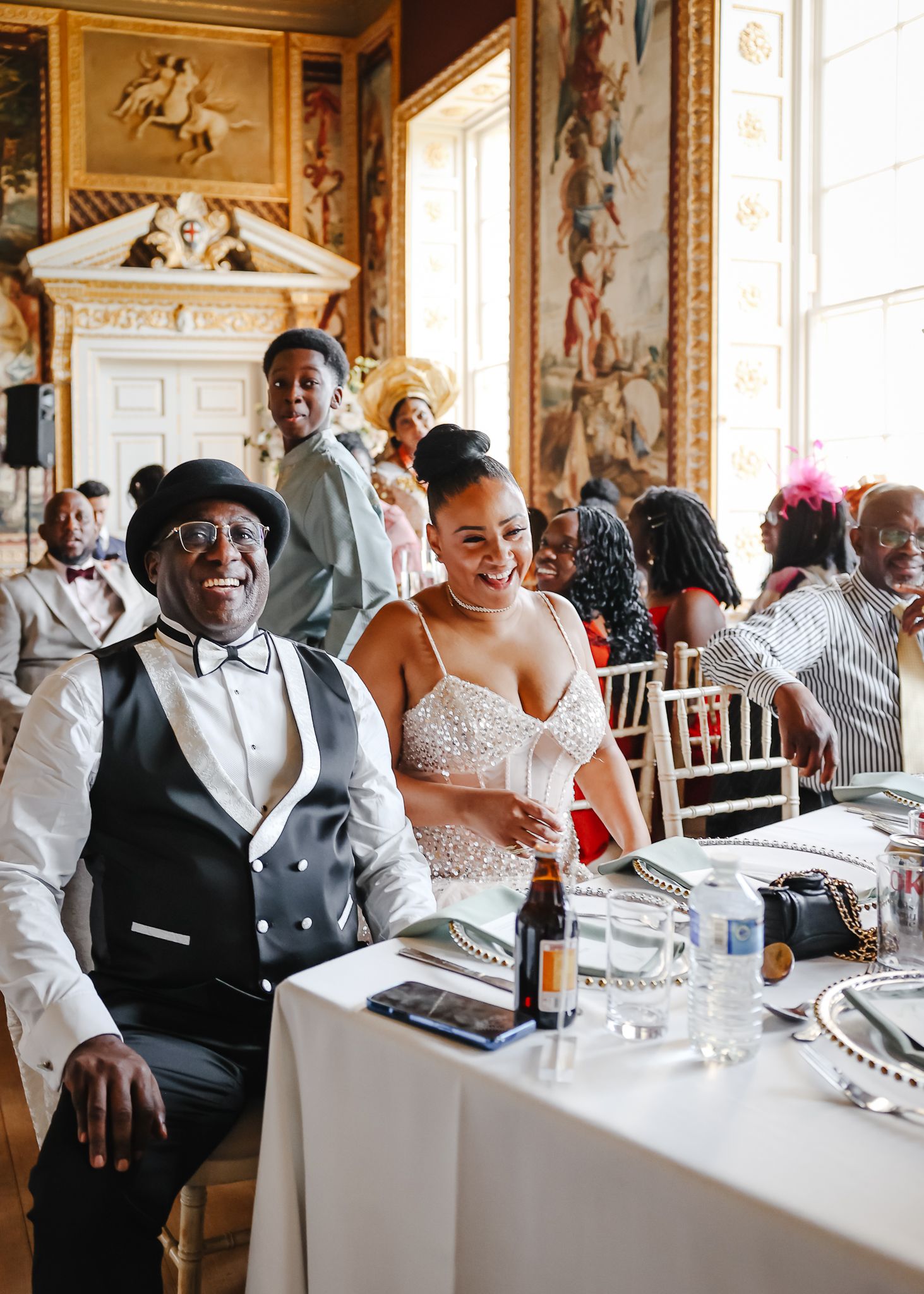 Wedding reception guests seated at tables in formal dining room wearing black and white attire.