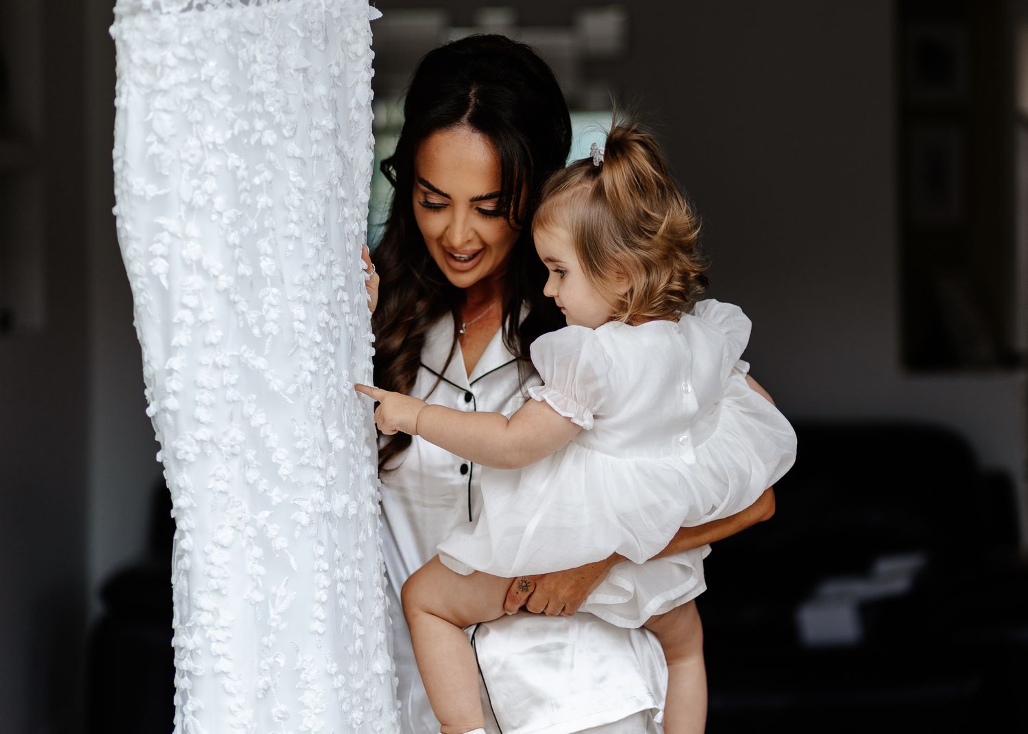 A tender moment between a parent and child wearing white against a dark background.