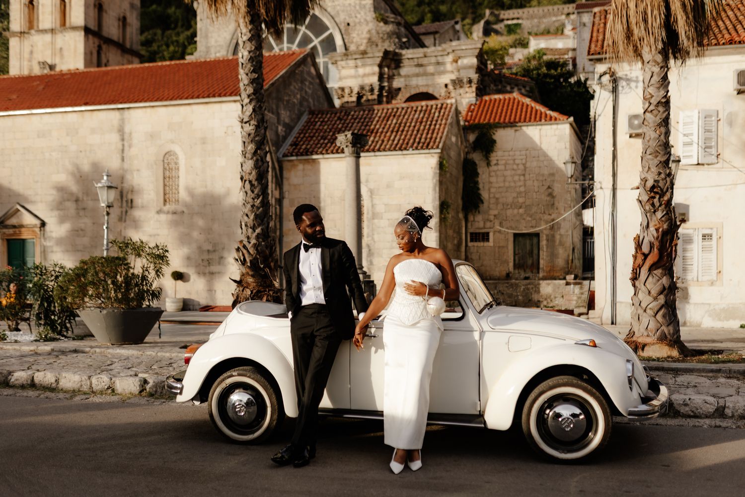 A series of wedding photos showing a couple posing with vintage cars and bicycles against stone building backdrops.