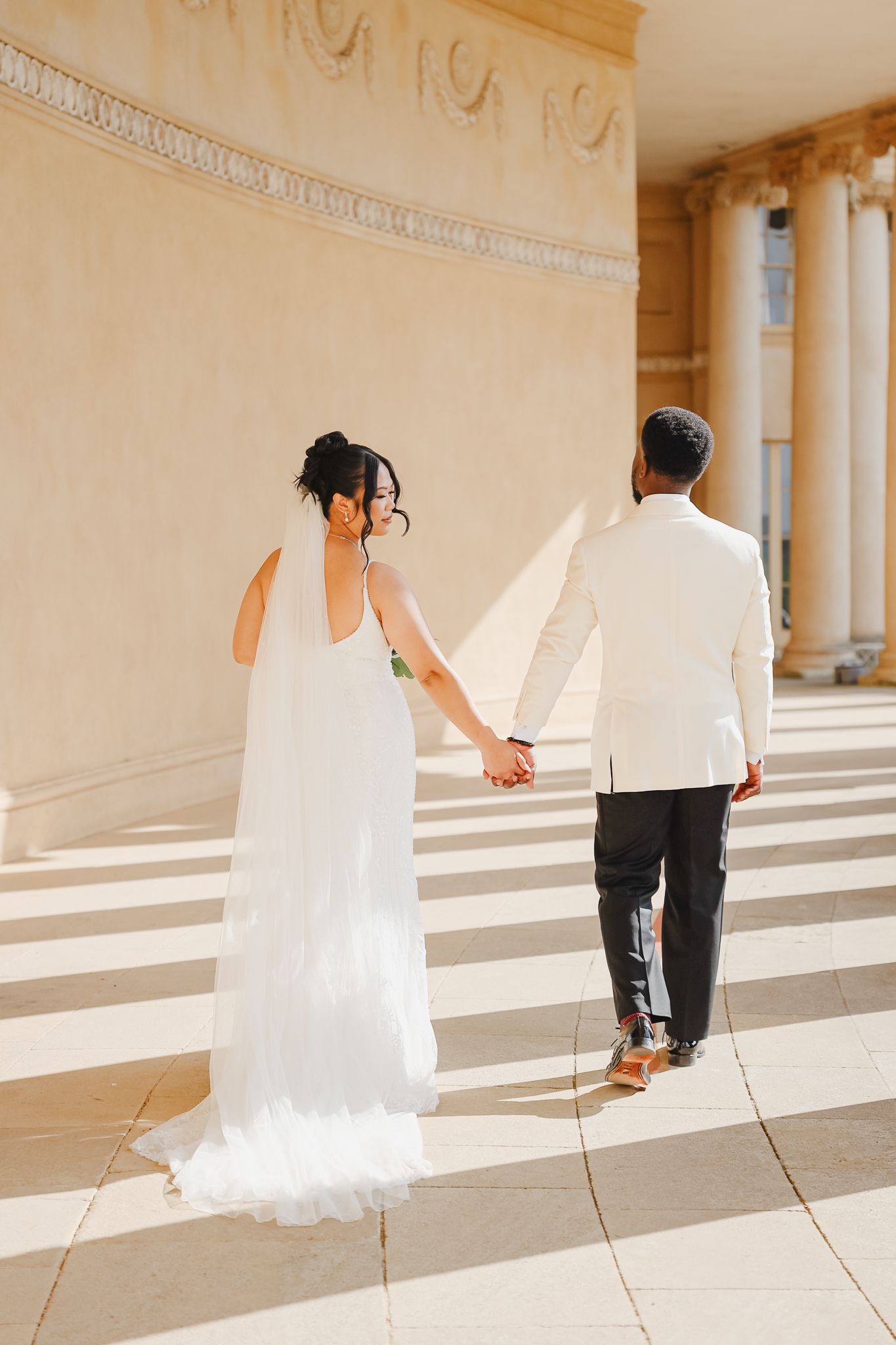 A sequence of photos showing a couple in wedding attire walking hand in hand through a sunlit colonnade.