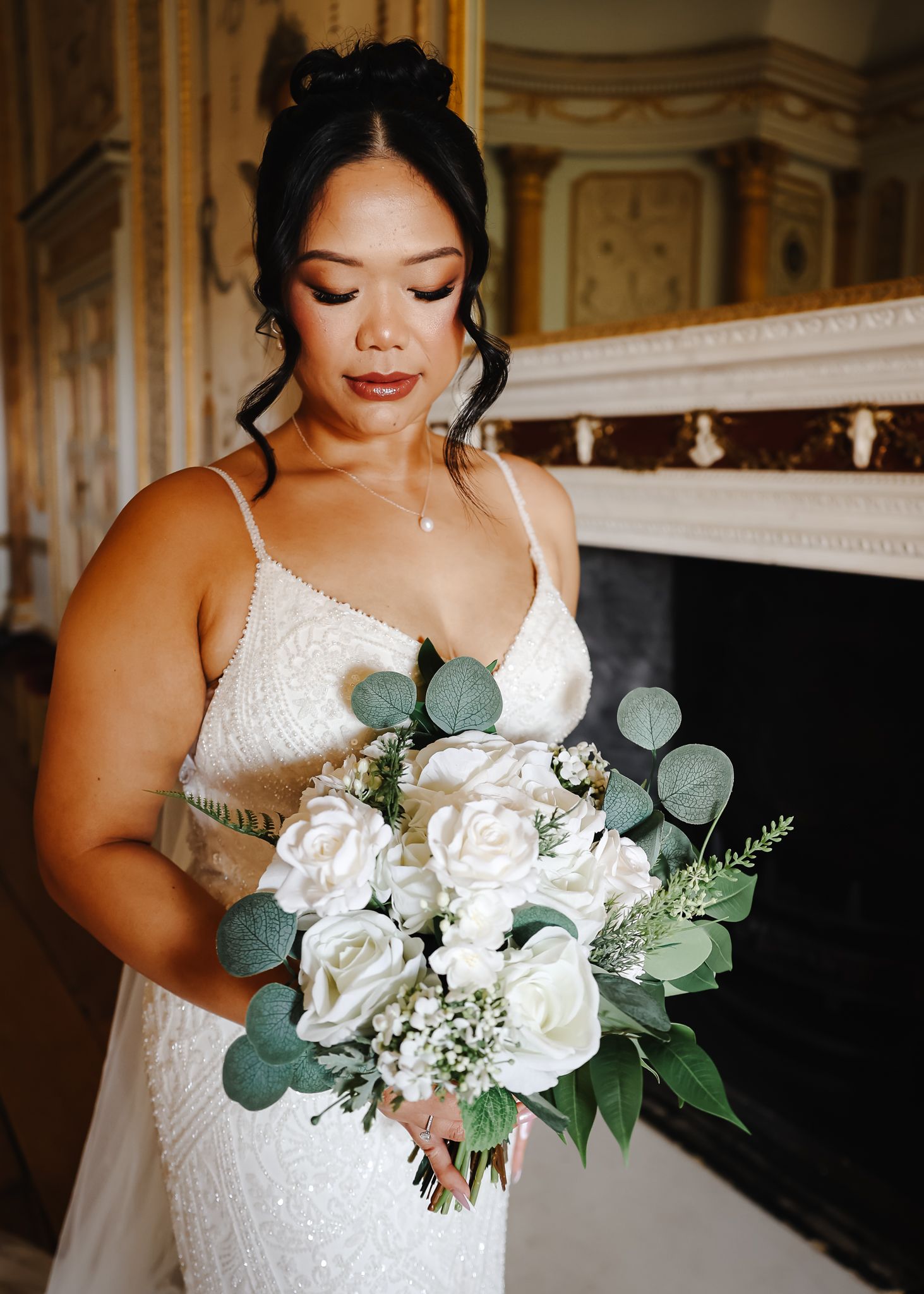 Elegant bridal portrait featuring a white lace wedding dress and romantic bouquet with white roses and eucalyptus leaves.