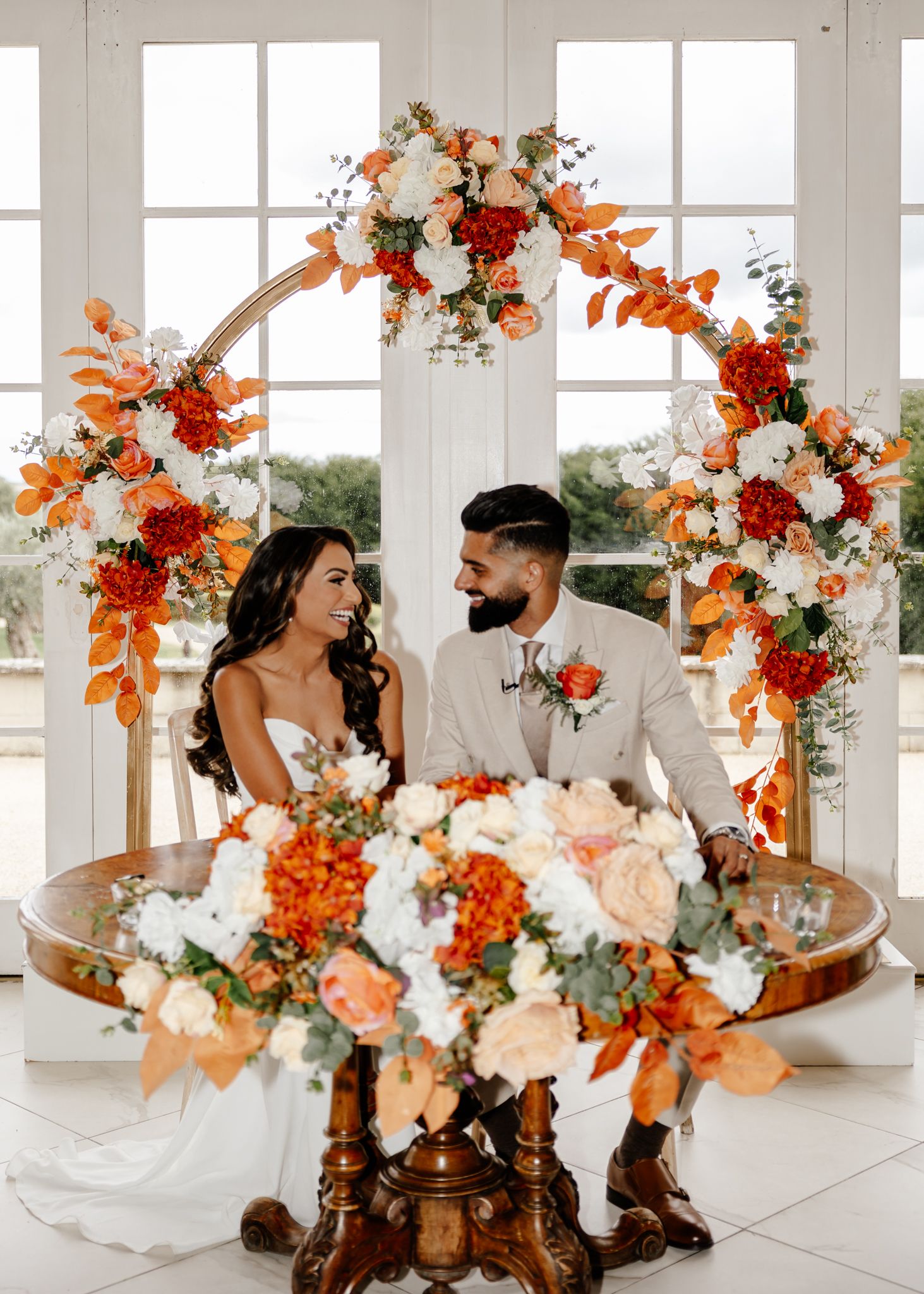 Wedding decor features elegant floral arrangements with orange and white blooms alongside rustic brown cowboy boots.
