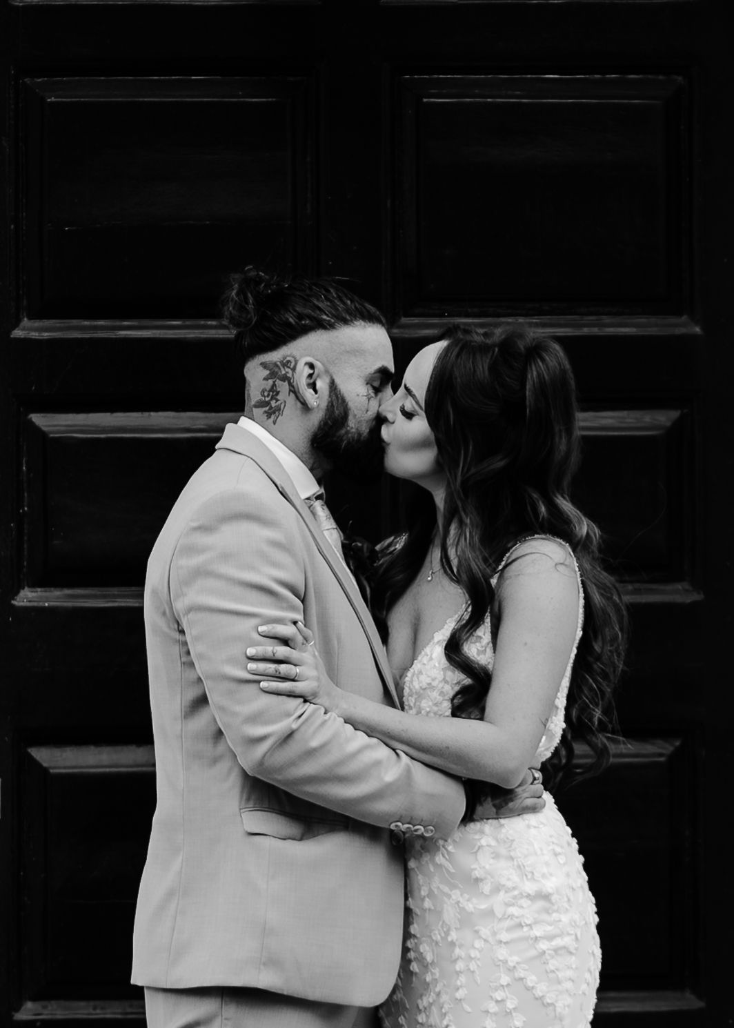 Black and white photo series showing a romantic kiss sequence between a couple in formal attire against a dark door.
