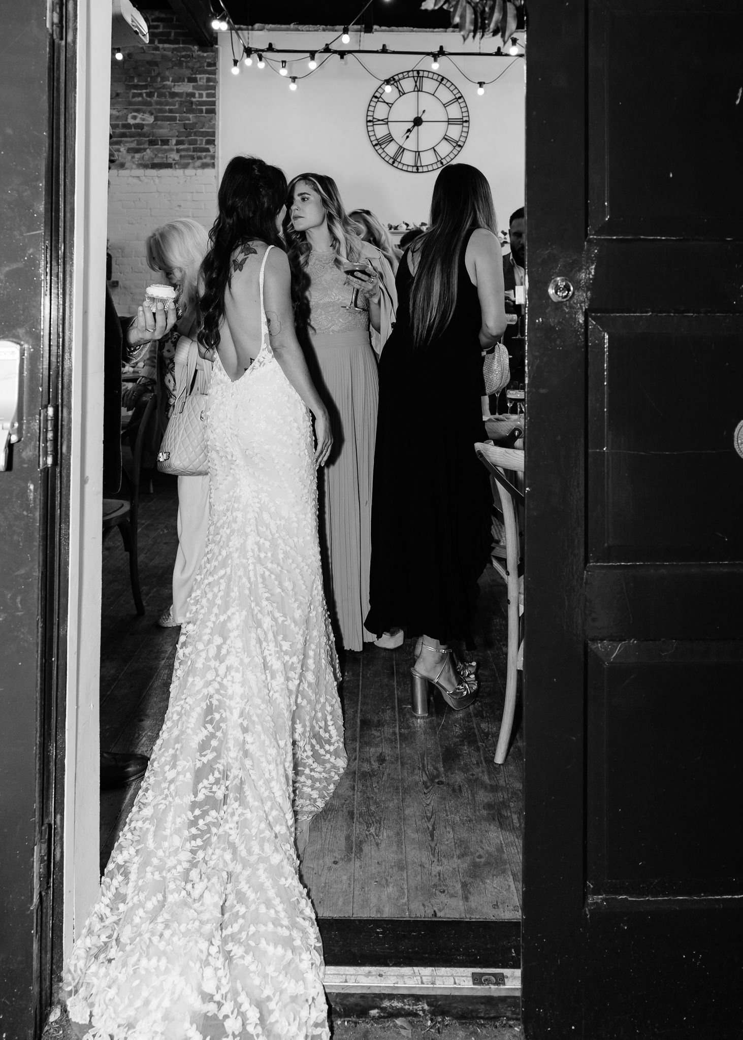 Multiple wedding dresses on display in a bridal boutique with vintage brick walls and decorative clock.