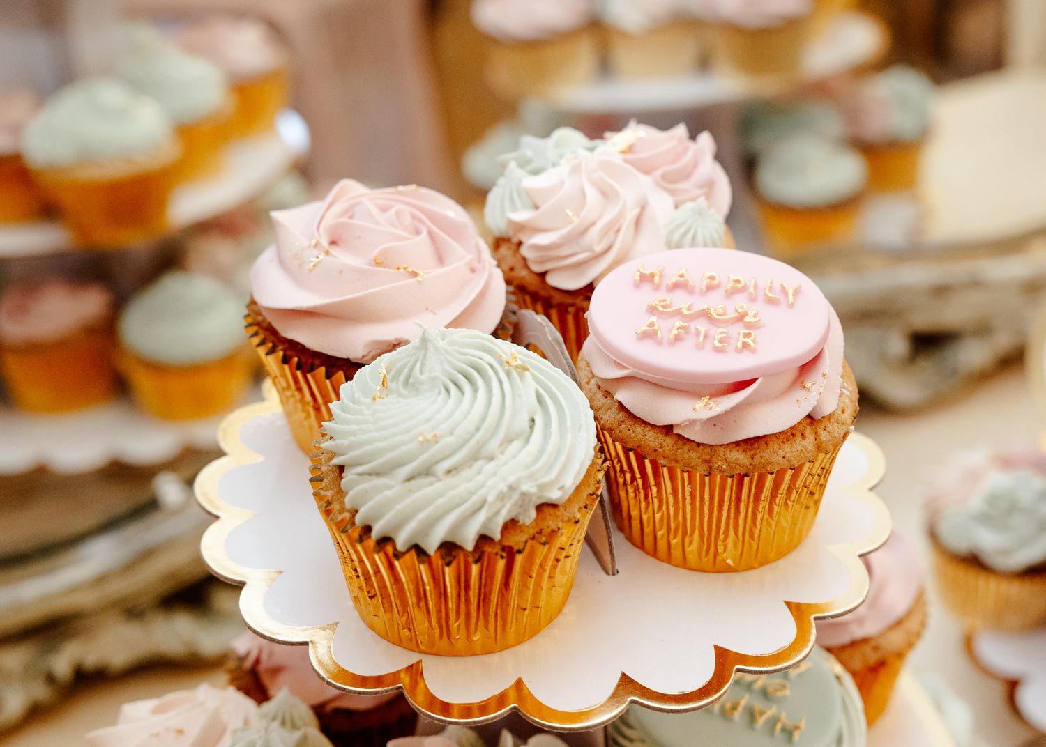 Elegant cupcakes decorated with pink and mint green frosting displayed on white scalloped plates for a special occasion.