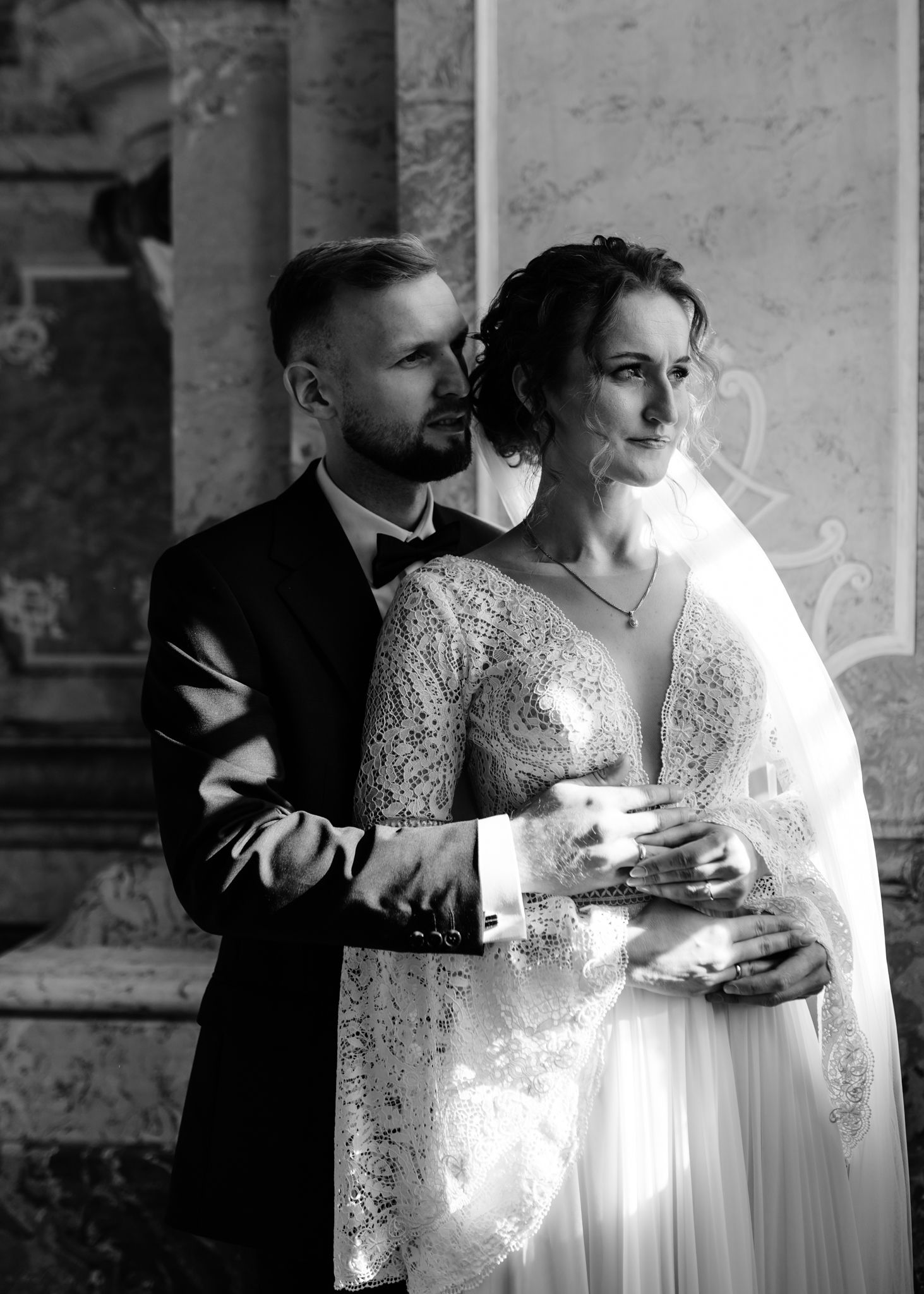 A romantic black and white wedding photo series showing intimate moments between newlyweds in a rustic interior setting.