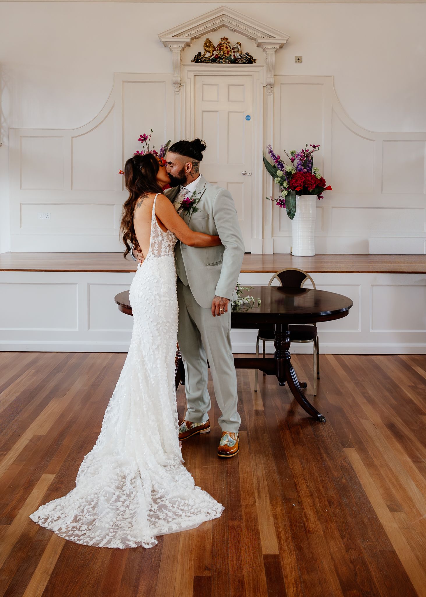 A romantic wedding moment with a couple embracing in a bright room with hardwood floors and elegant white decor.
