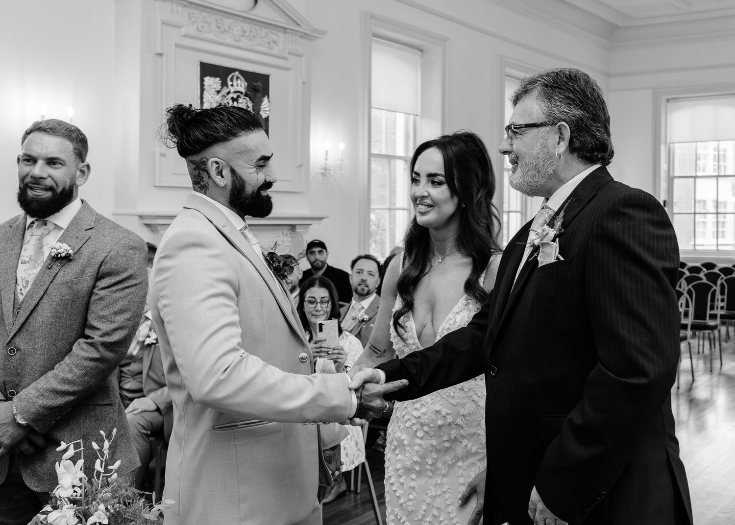 A black and white photo sequence showing wedding guests dancing and celebrating at an elegant reception hall.