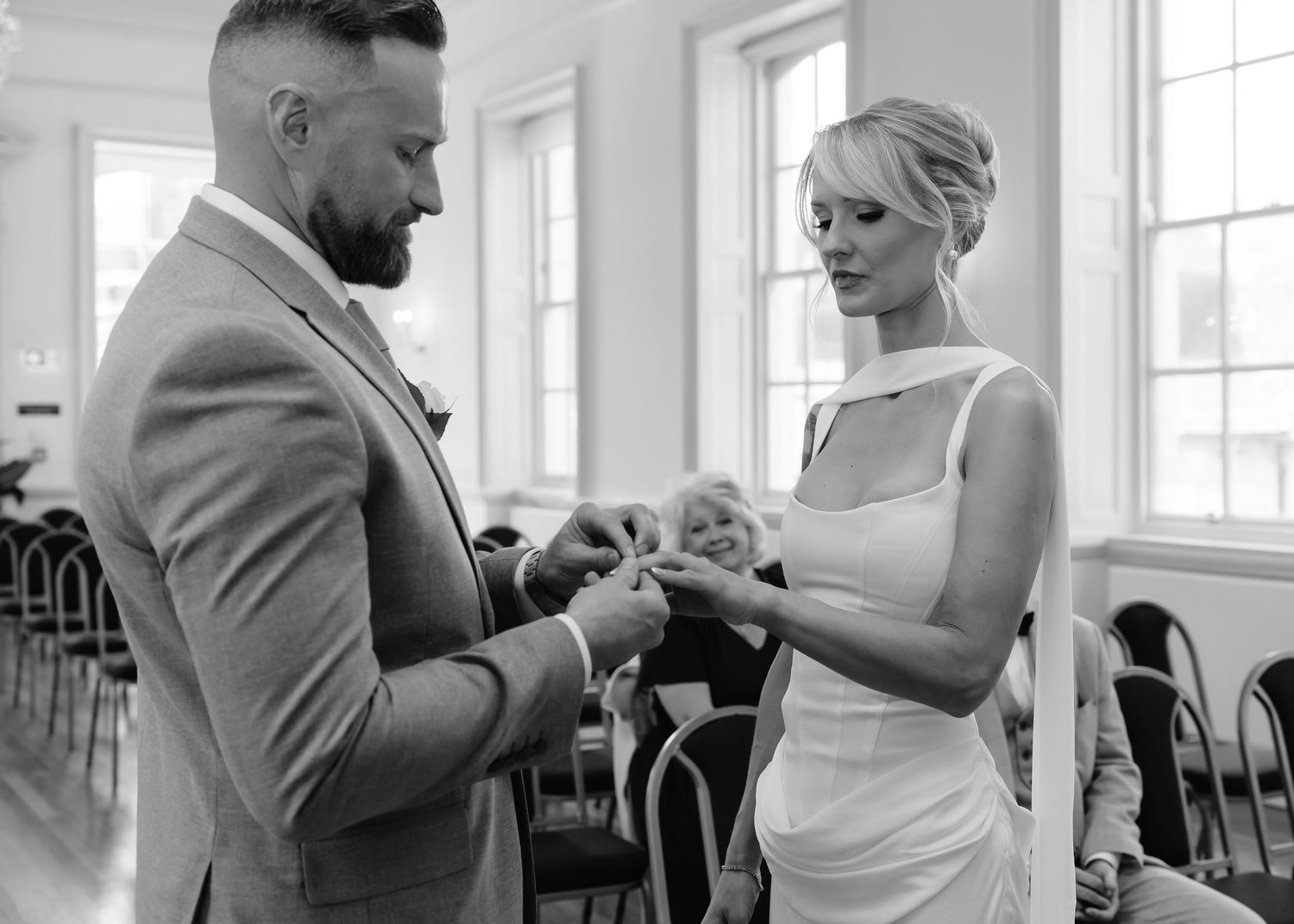 Bride and groom exchanging rings during intimate wedding ceremony in black and white.