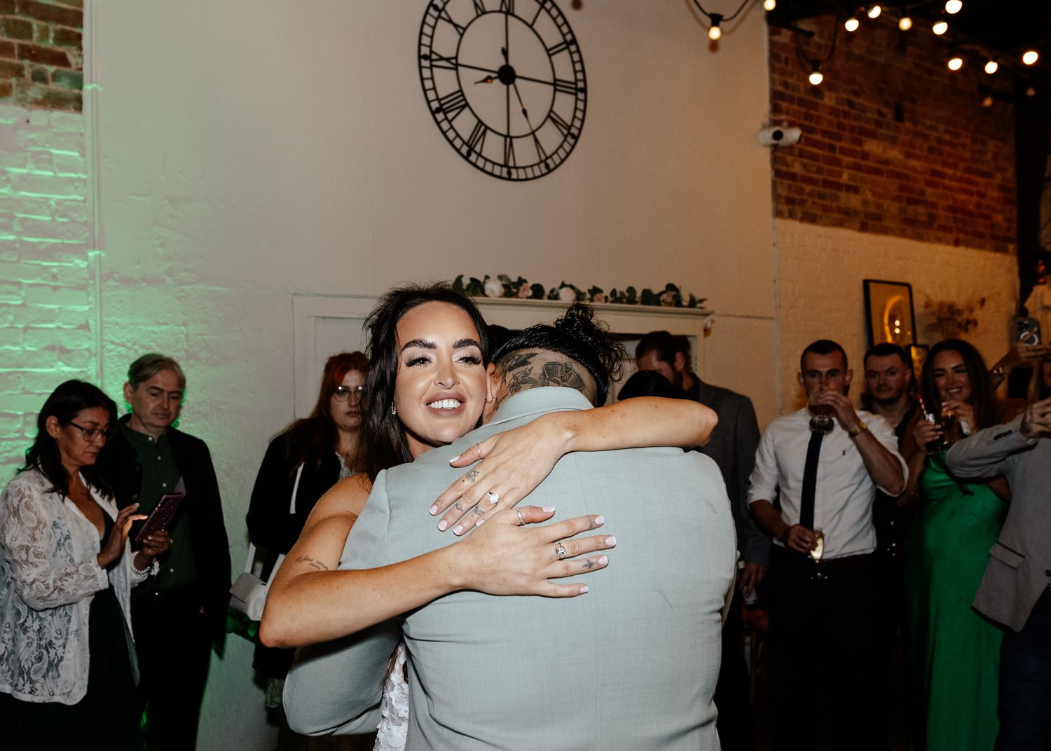 A sequence of candid dance floor moments at a wedding reception with string lights and exposed brick walls in the background.