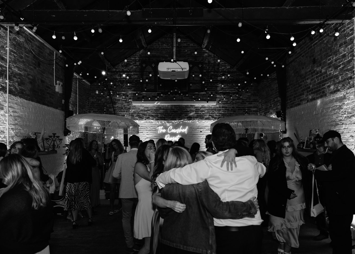A crowded dance floor with people dancing under twinkling lights at a nightclub party.