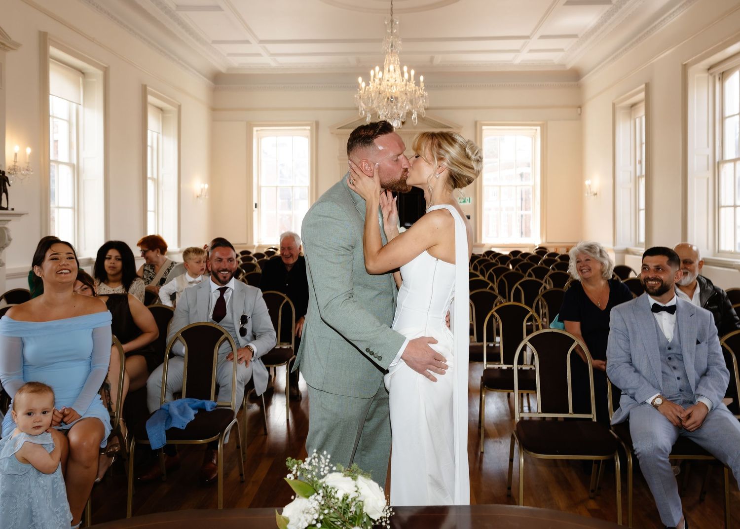 Newlyweds share first kiss as married couple before seated wedding guests.