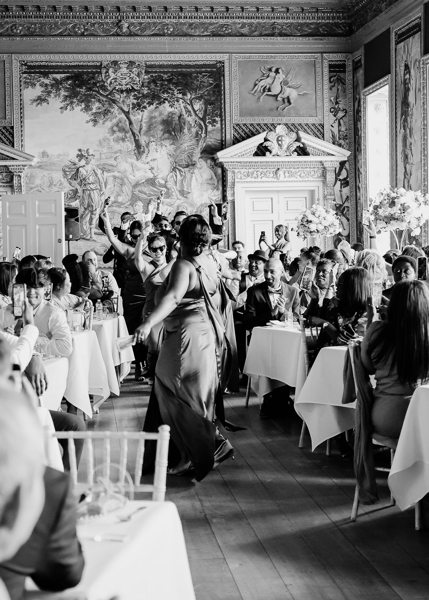 A panoramic view of an elegant wedding reception in a grand ballroom with white-clothed tables and ornate decor.