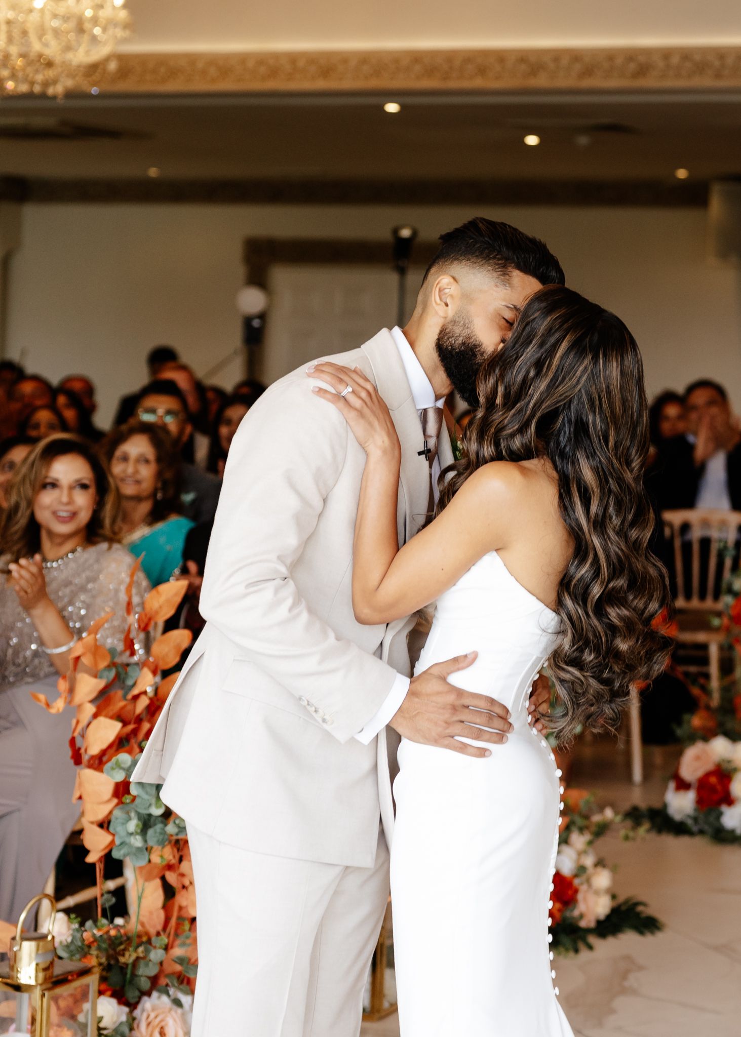 A couple shares their first dance at a wedding reception while guests watch and celebrate in a beautifully lit ballroom.