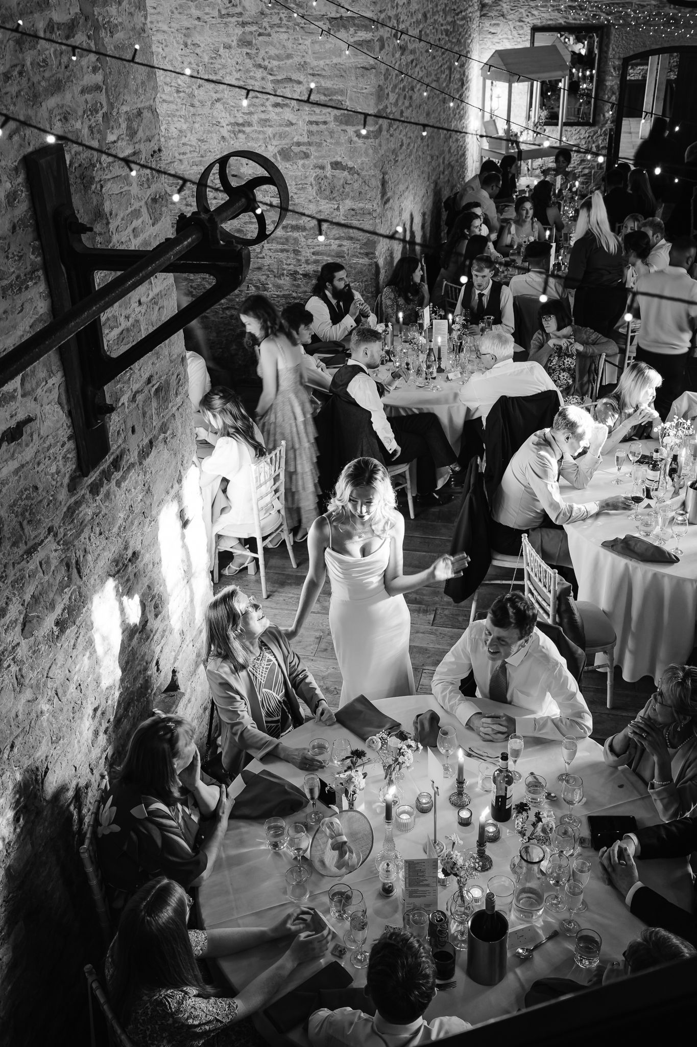 A candlelit wedding reception in a rustic stone-walled venue with tables set for dinner guests.