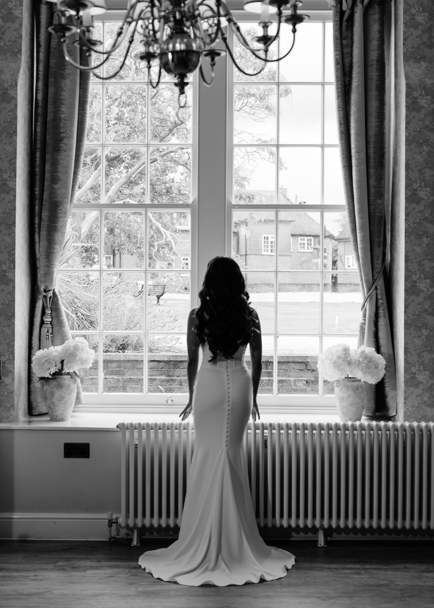 A black and white panoramic series showing a wedding dress silhouette against bright windows in an elegant room.