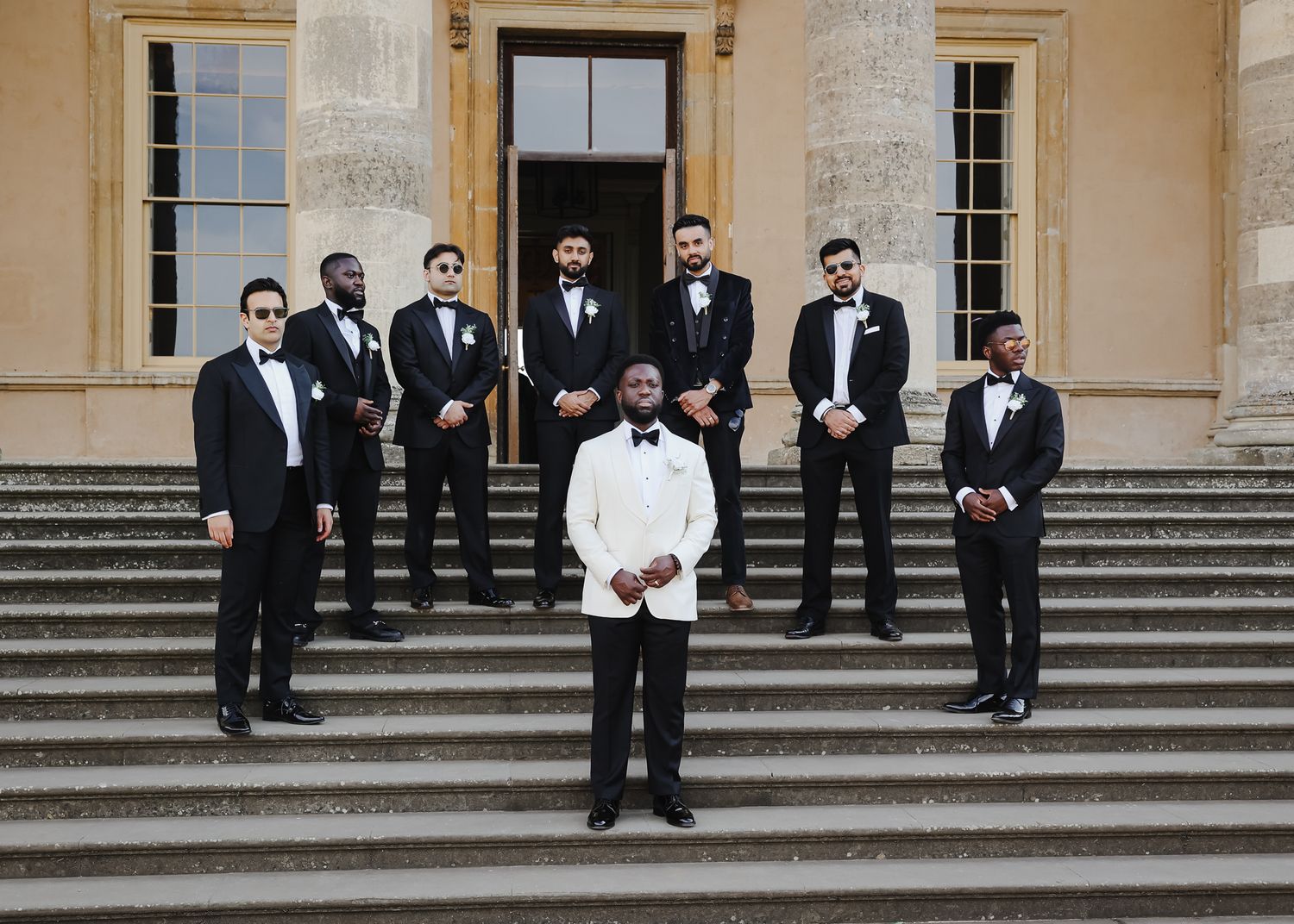 Wedding party members in formal attire standing on elegant stone steps.