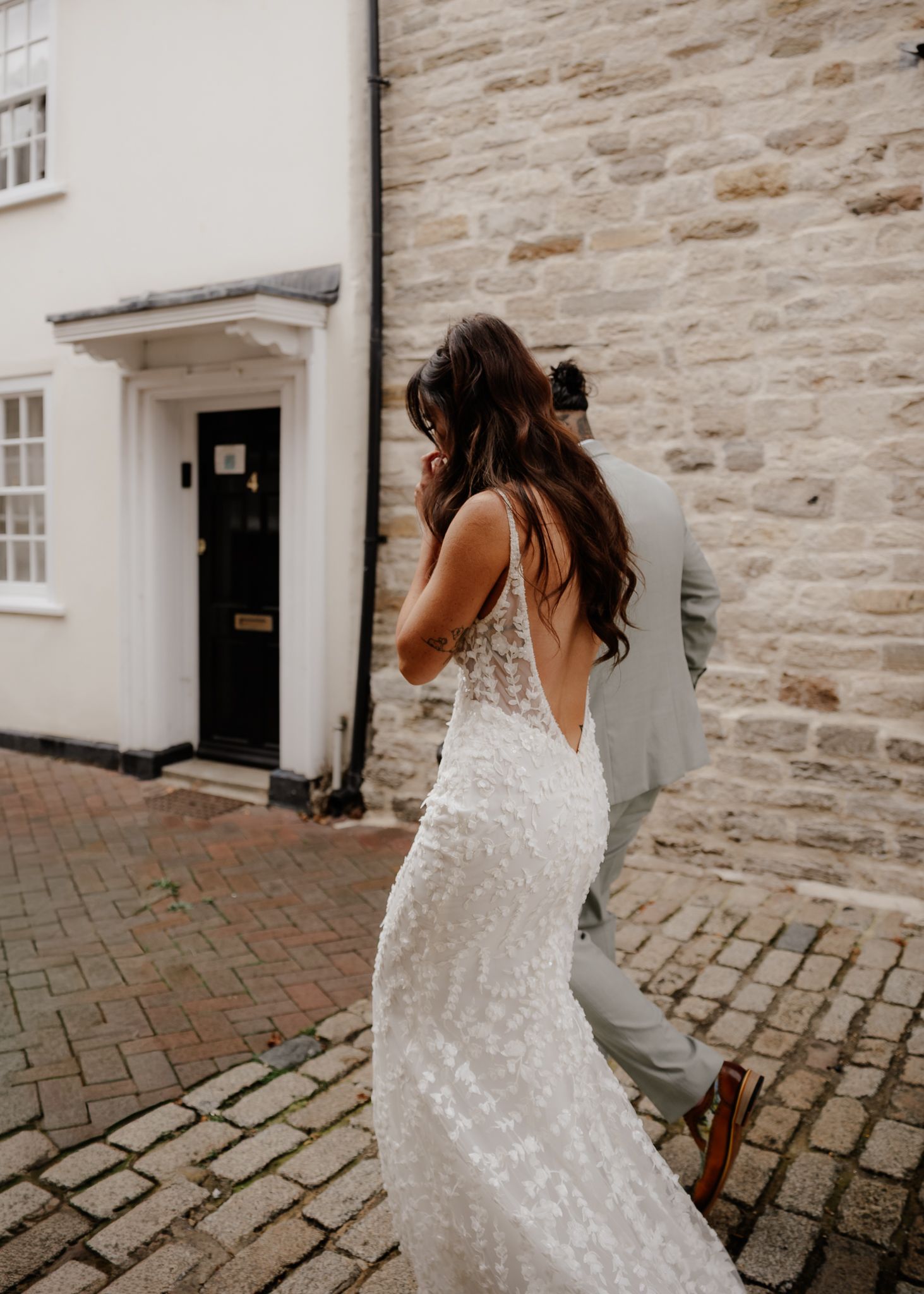 A wedding couple shares intimate moments against a rustic stone wall and cobblestone path.