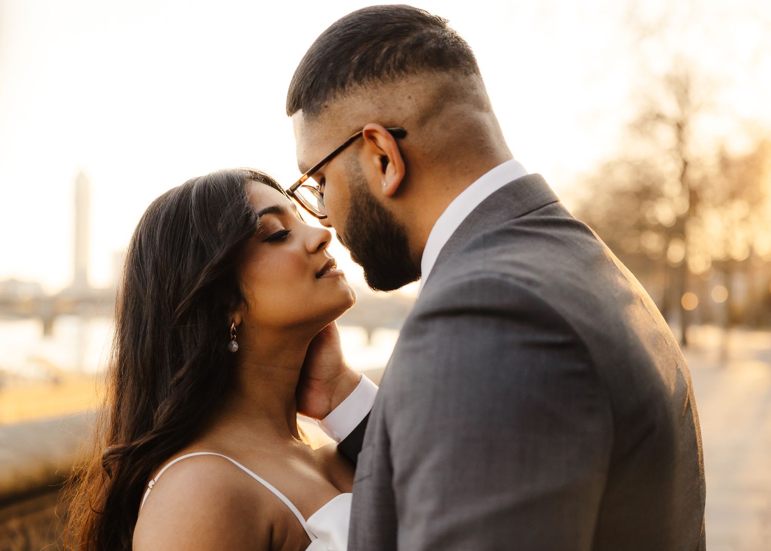 A romantic couple embraces during sunset in a warm golden light outdoors.