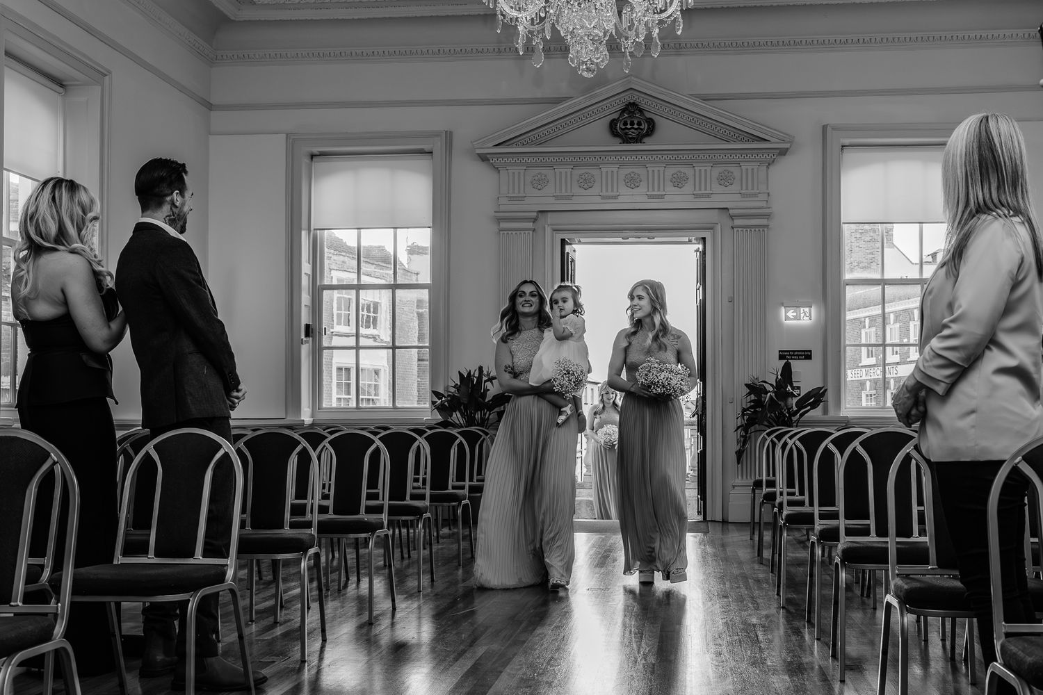 An elegant ballroom interior with chandeliers and large windows in black and white.