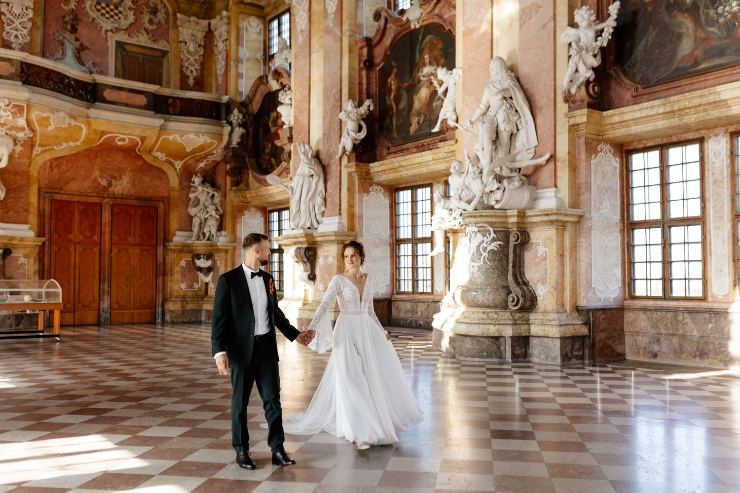 Elegant baroque wedding venue with ornate marble columns and gilded decorations in a historic palace ballroom.