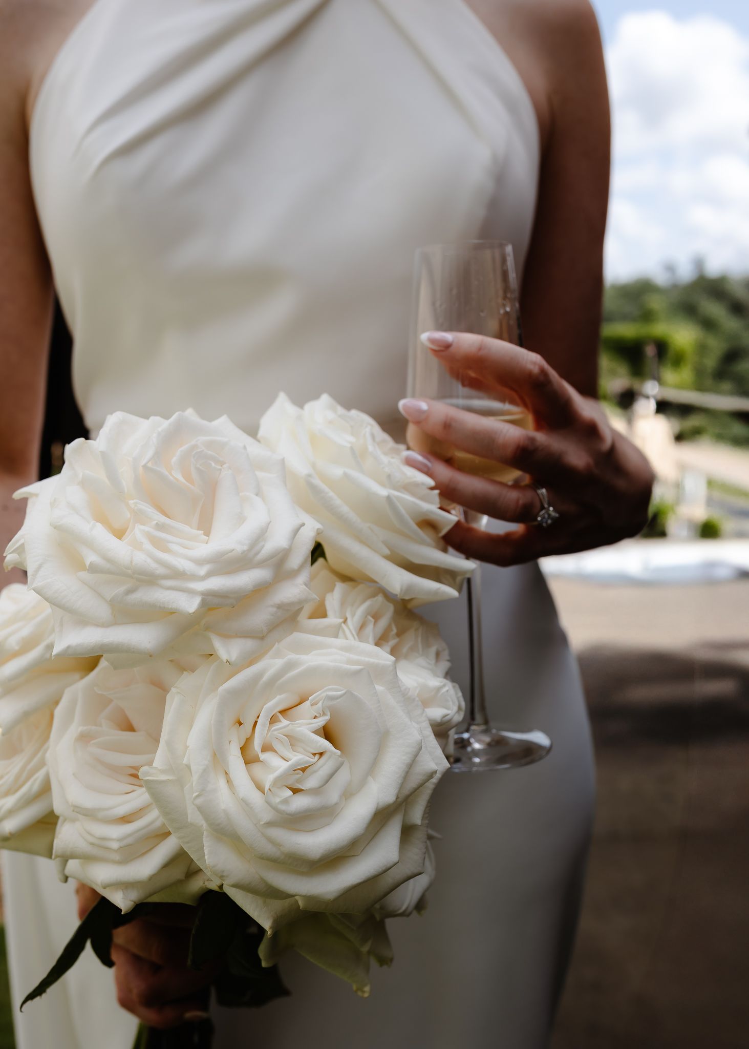 Close-up of elegant white rose bouquets held by people in formal wedding attire.