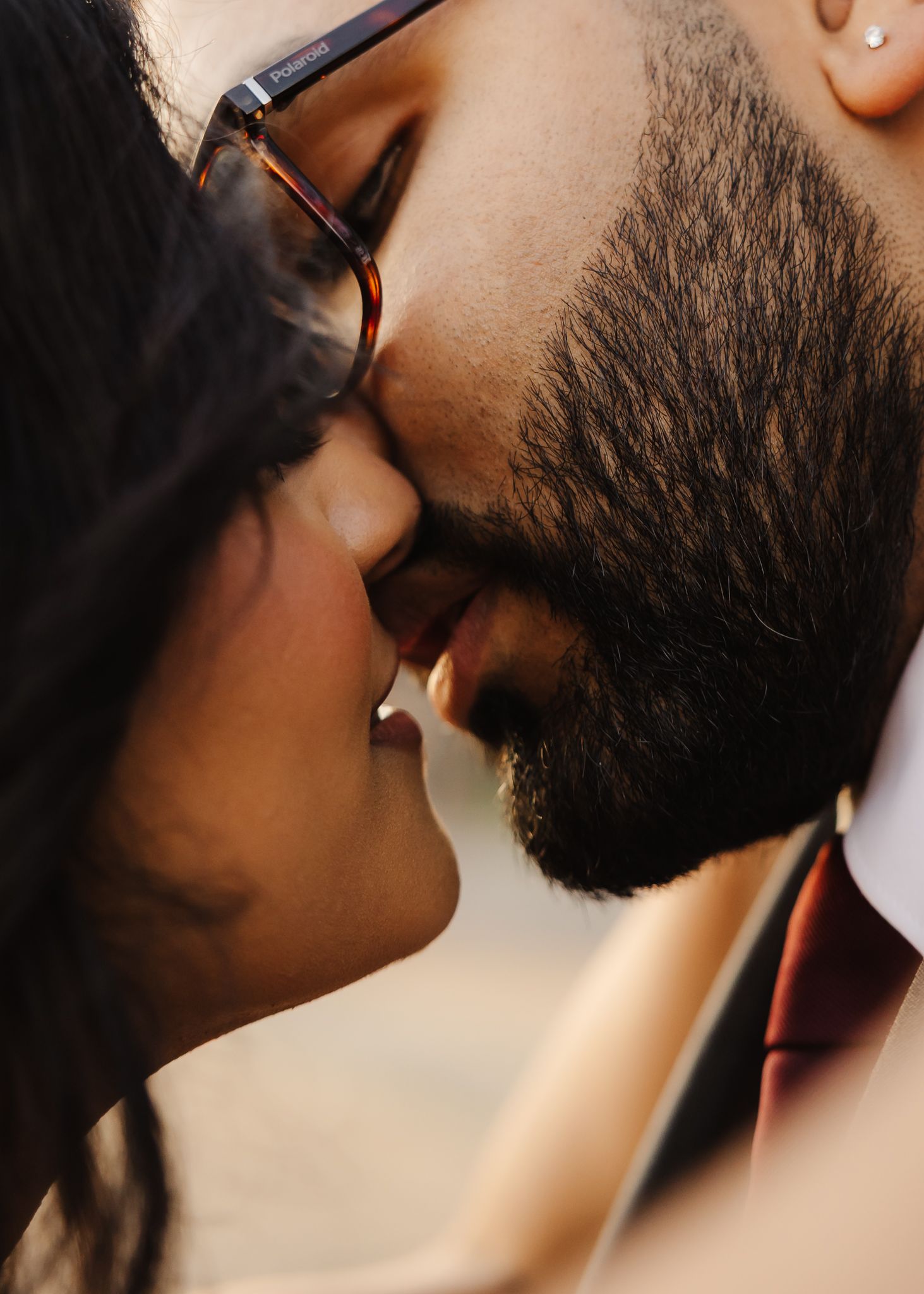 Close-up profile view of a bearded person with glasses in a romantic kissing moment.