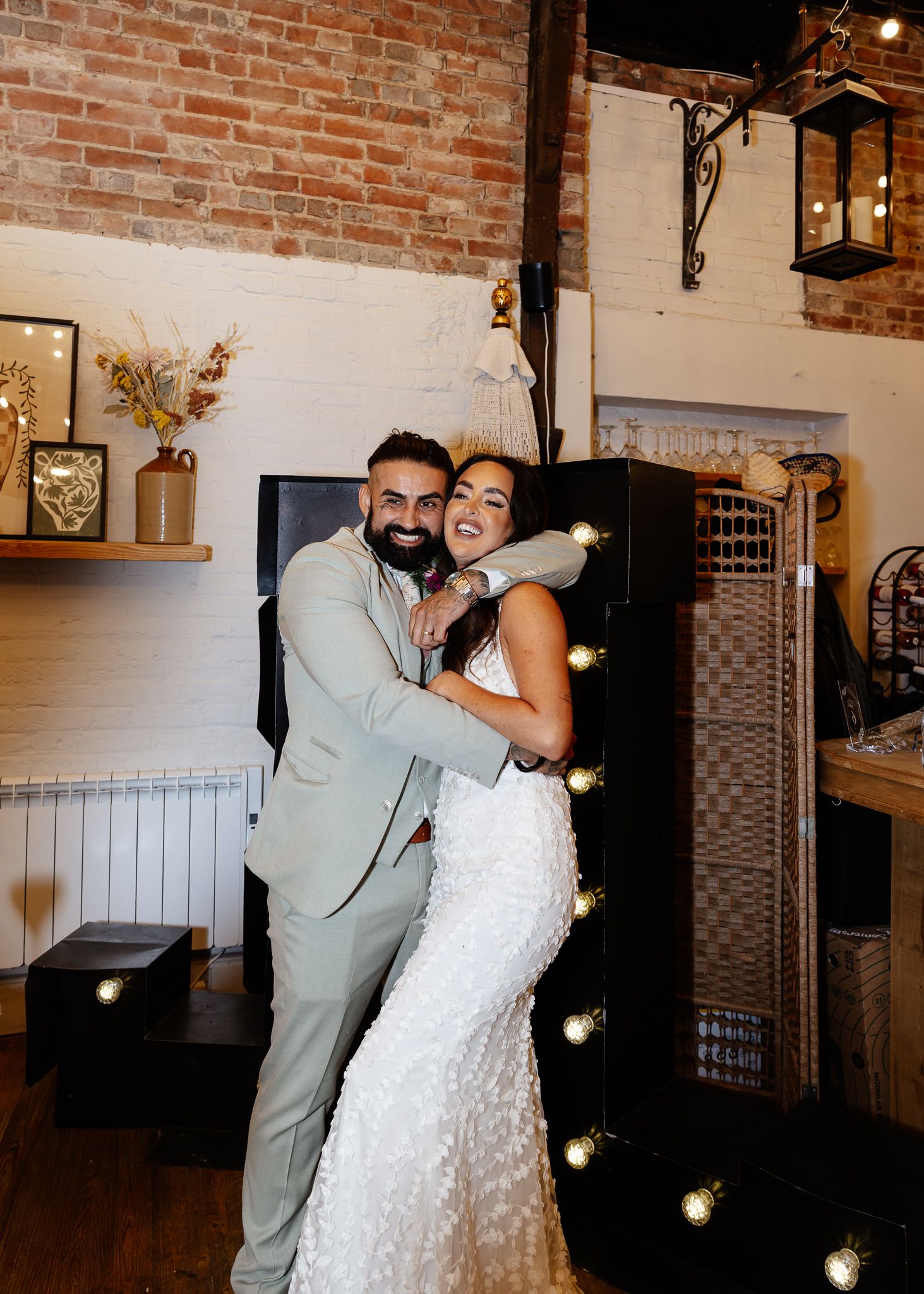 A couple shares their first dance in a rustic brick-walled venue with hanging string lights.