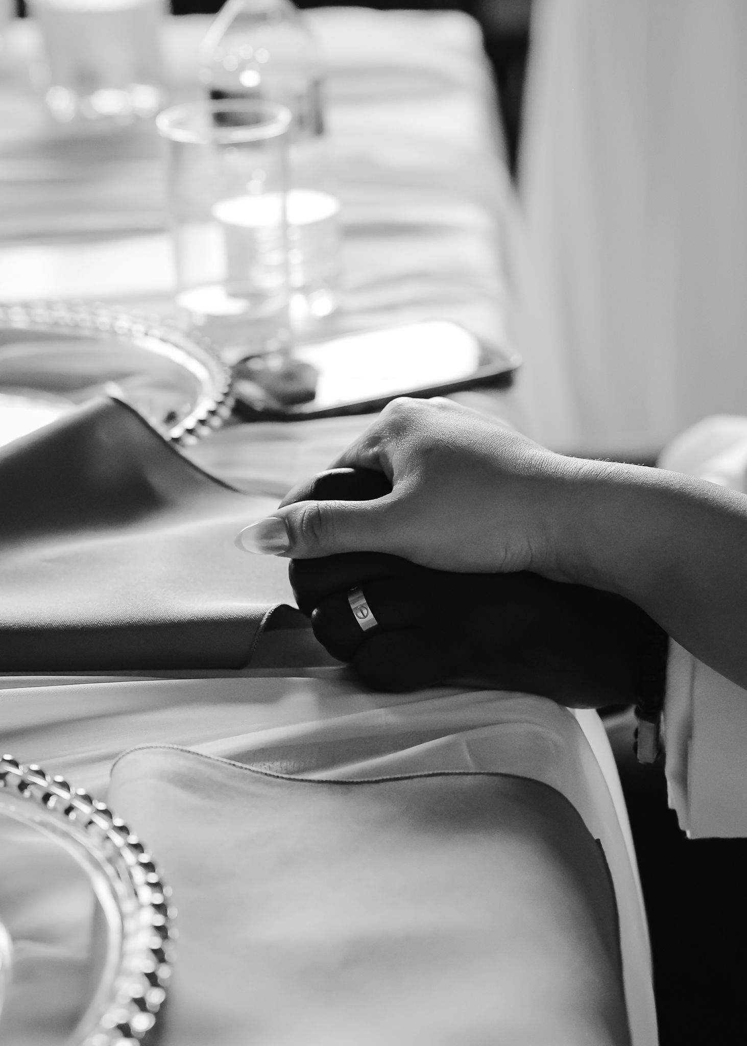 A close-up view of hands writing on paper with a pen in black and white.