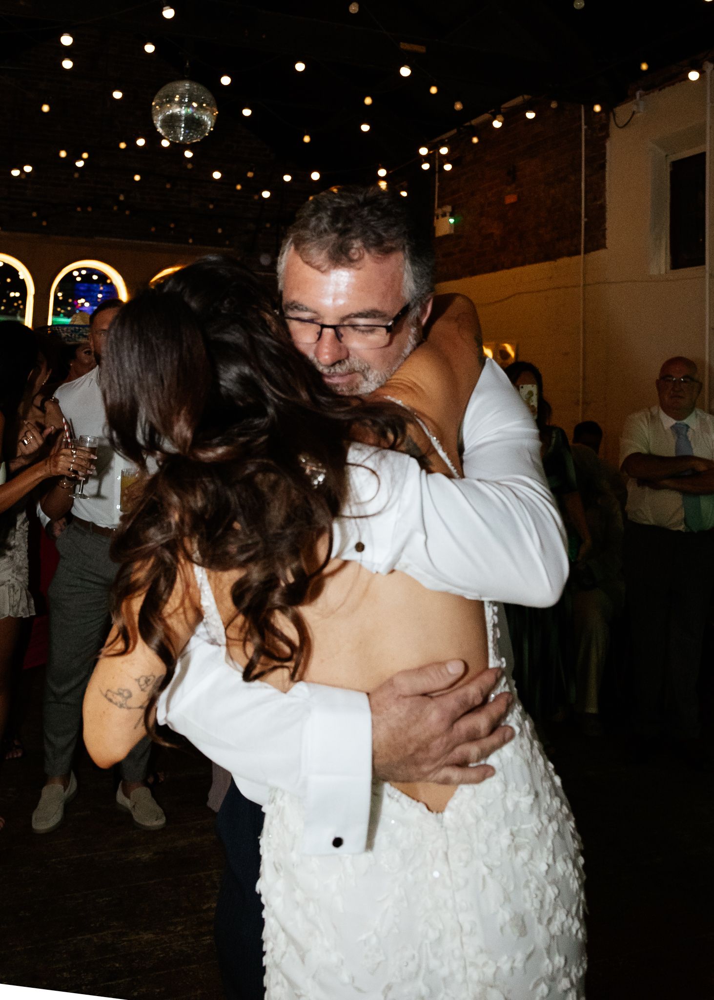 Romantic slow dance under twinkling lights at indoor wedding reception venue.