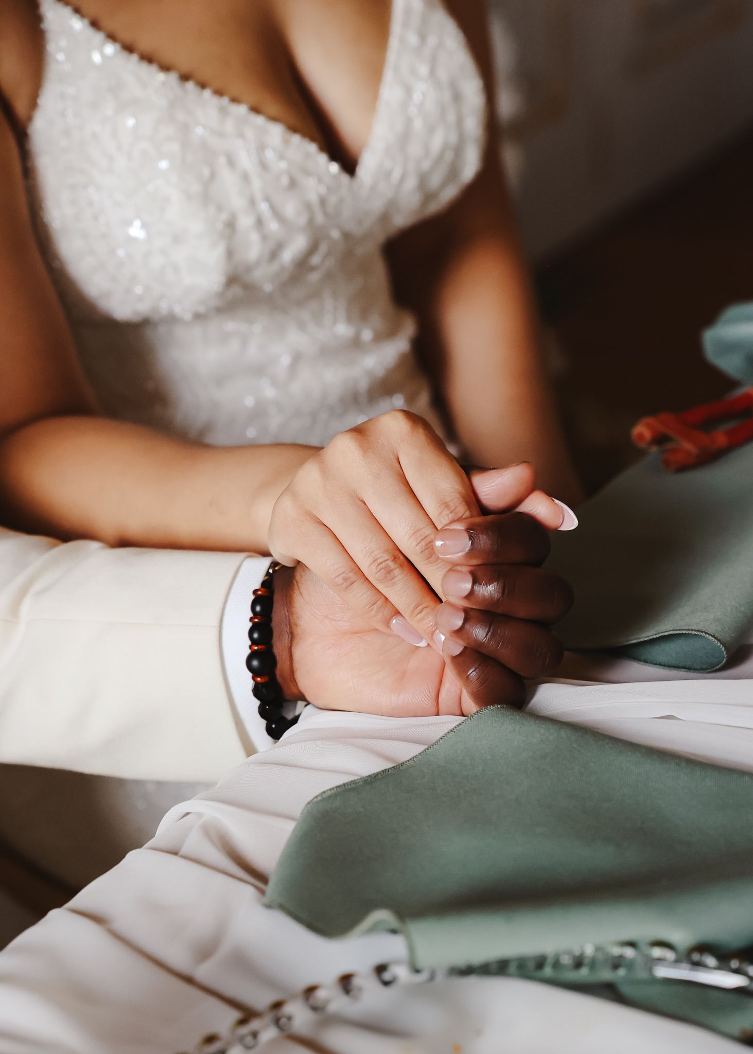 Close-up of hands wearing white beaded dress signing documents.