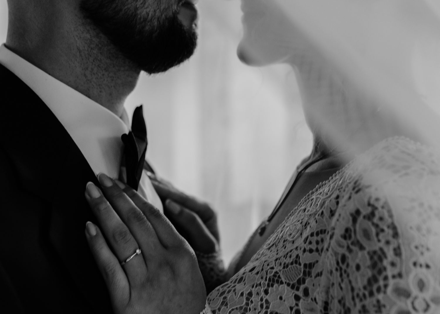 Close-up black and white detail of wedding couple's intimate embrace.