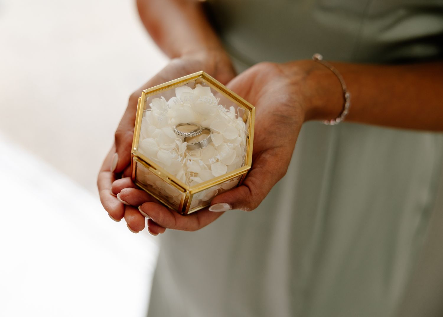 Hands holding small decorative boxes with a rustic vintage style at a wedding event.