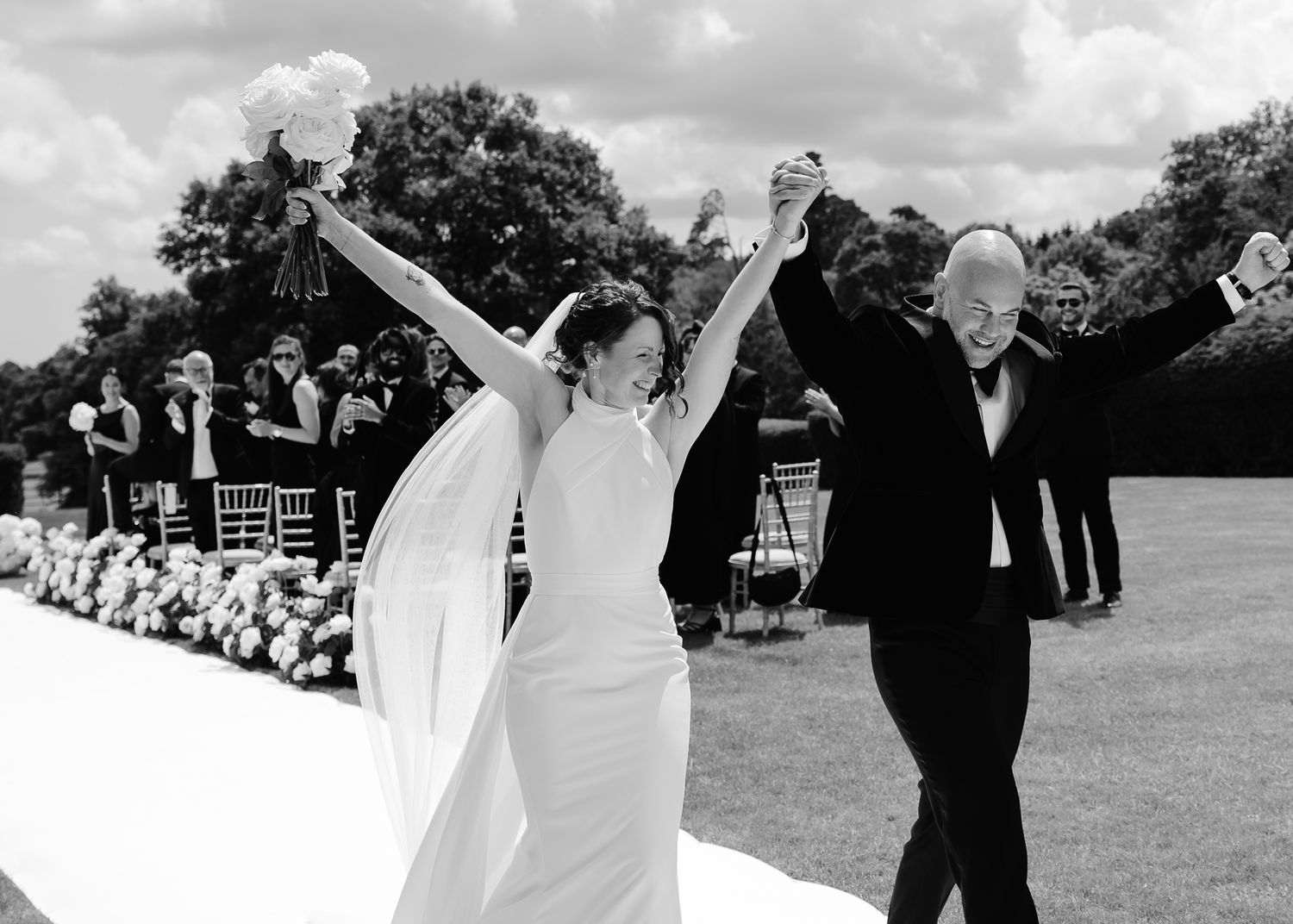 Black and white wedding photos showing joyful moments on a grassy estate.