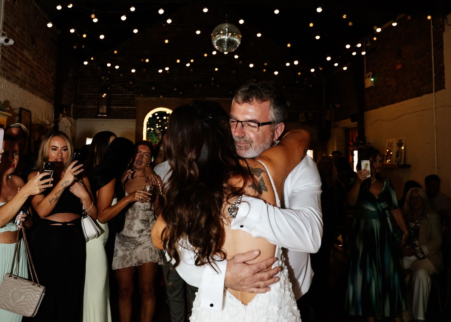 Couples dancing together at a wedding reception under twinkling lights on the dance floor.