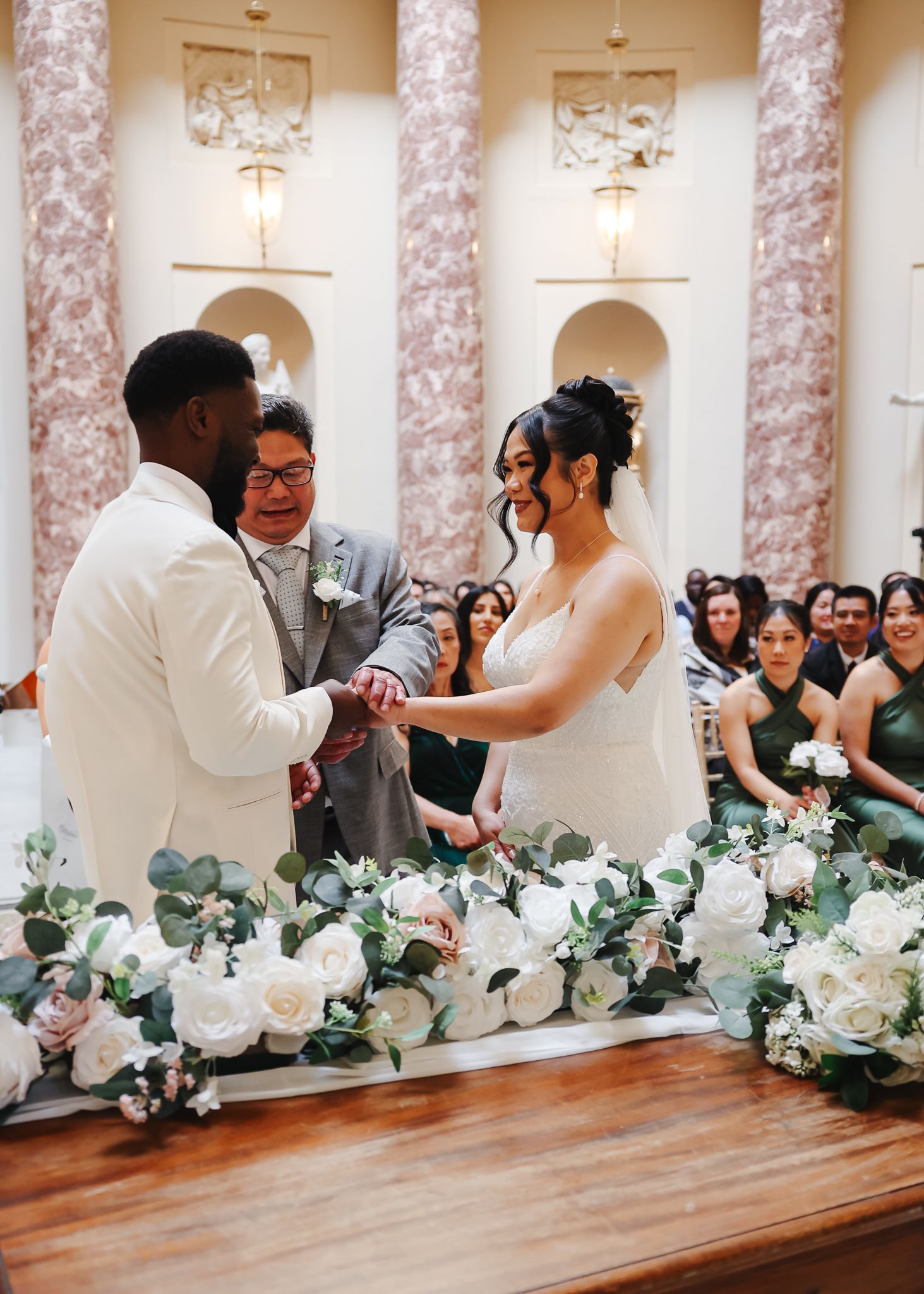 Wedding reception table decorated with white floral arrangements and marble columns in an elegant venue.