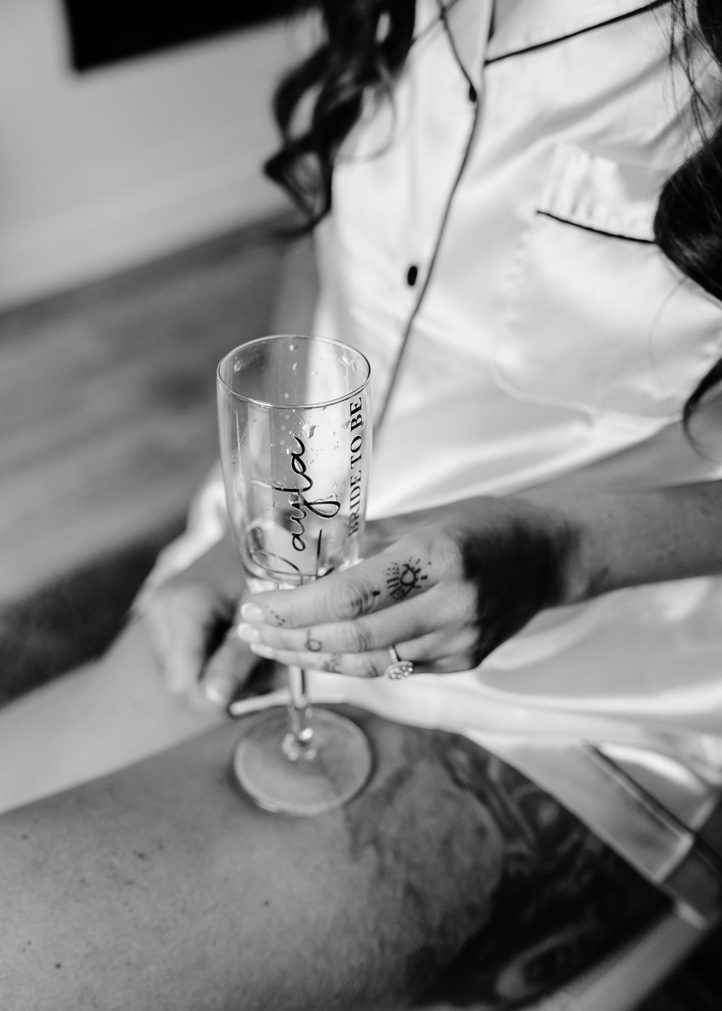 Person in white silk robe holding a champagne glass in black and white photography.