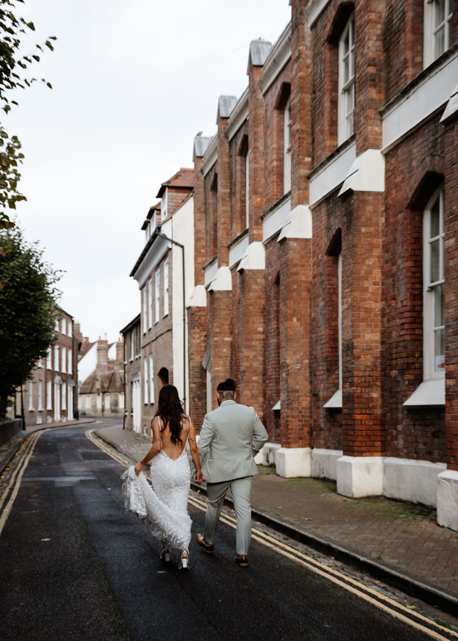 A series of photos showing people walking and posing along a brick-lined street with terraced houses.