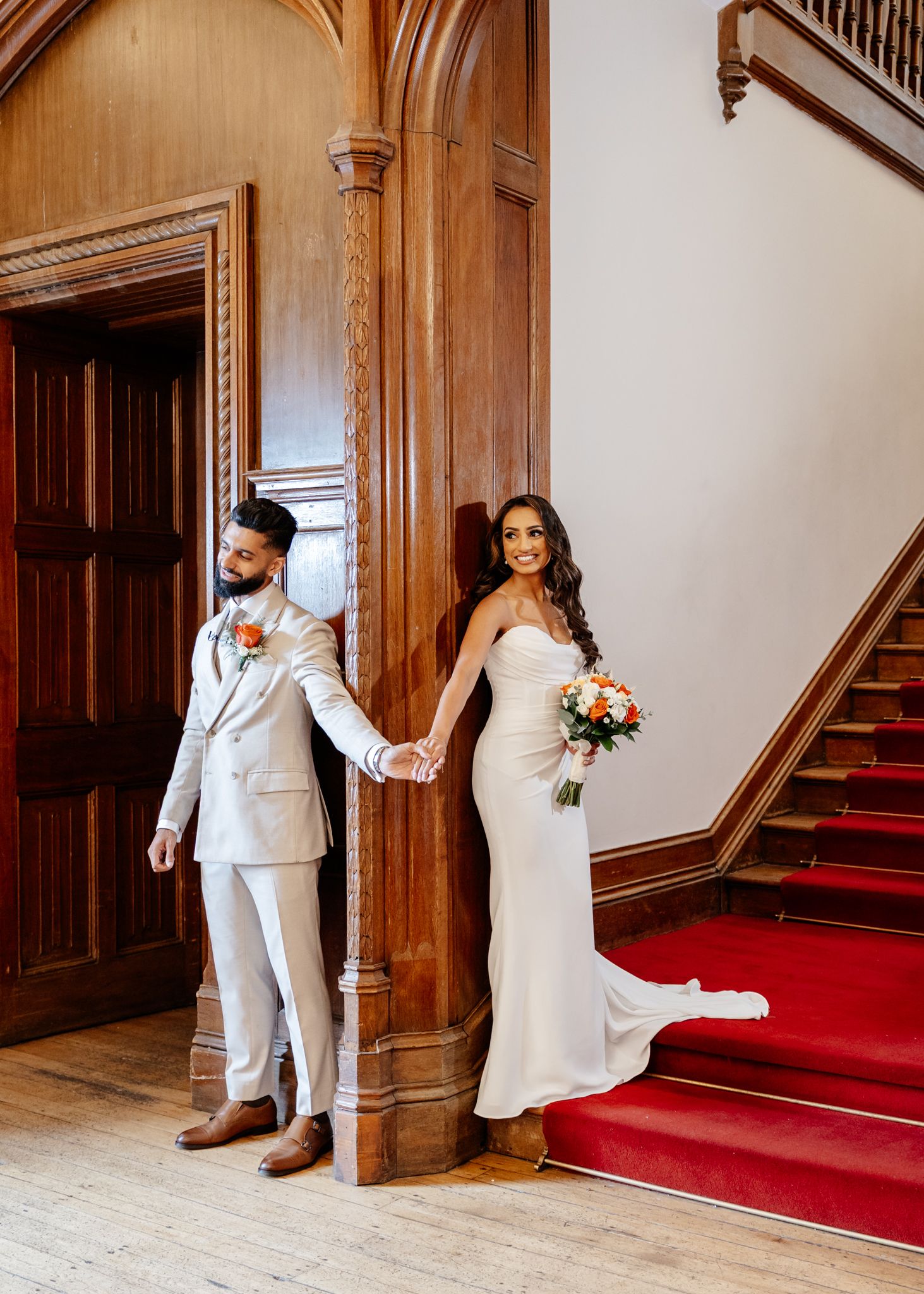 A romantic wedding photo series showing a couple in white attire posing playfully near a grand wooden staircase.