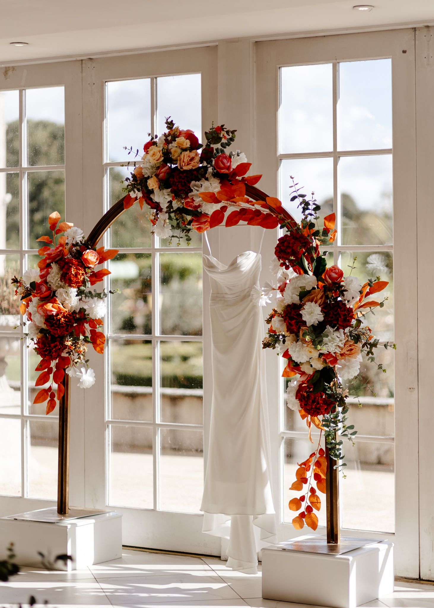 Elegant wedding venue interior with white French doors and autumn-colored floral arrangements.