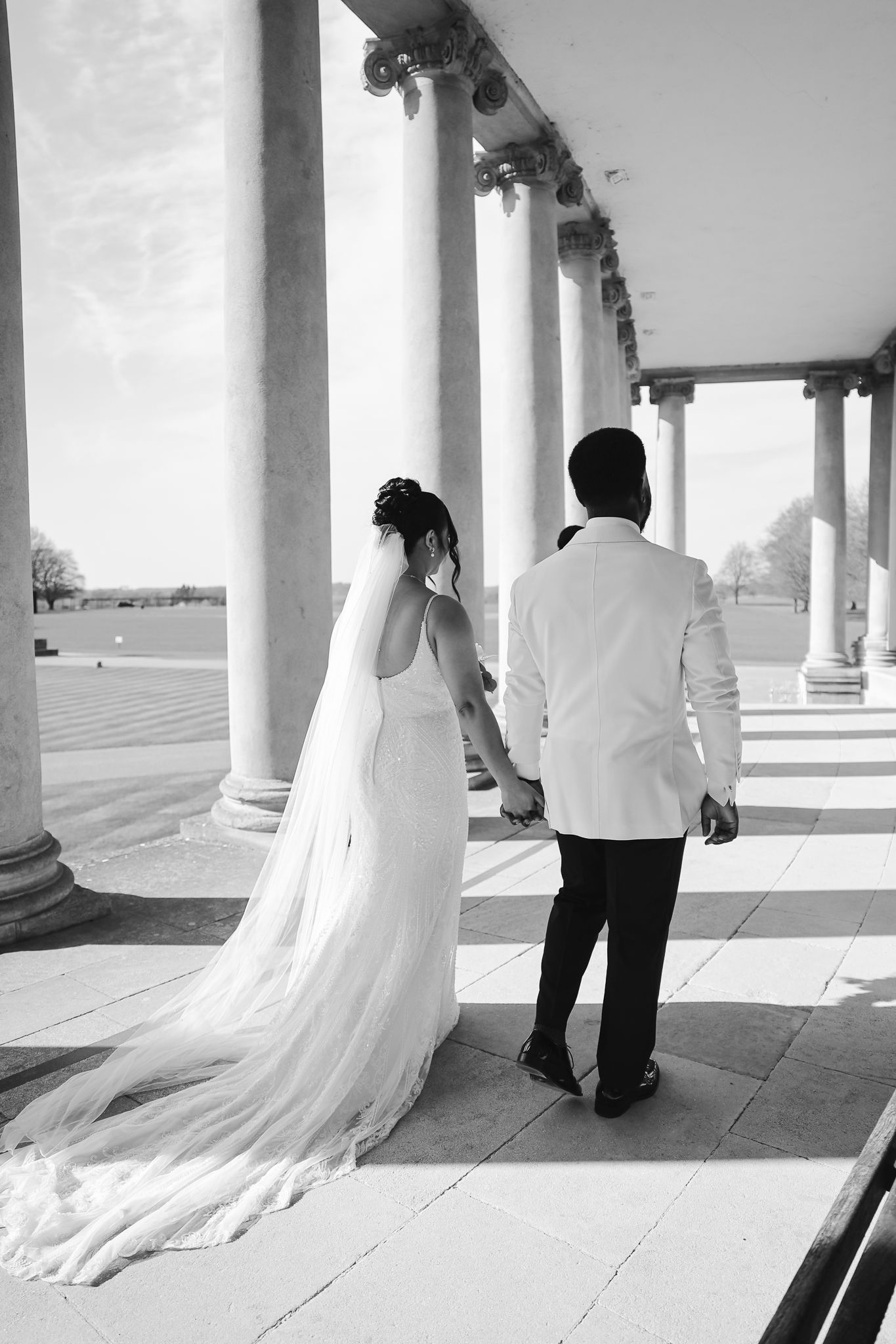 Black and white series of wedding couple walking along columned corridor.