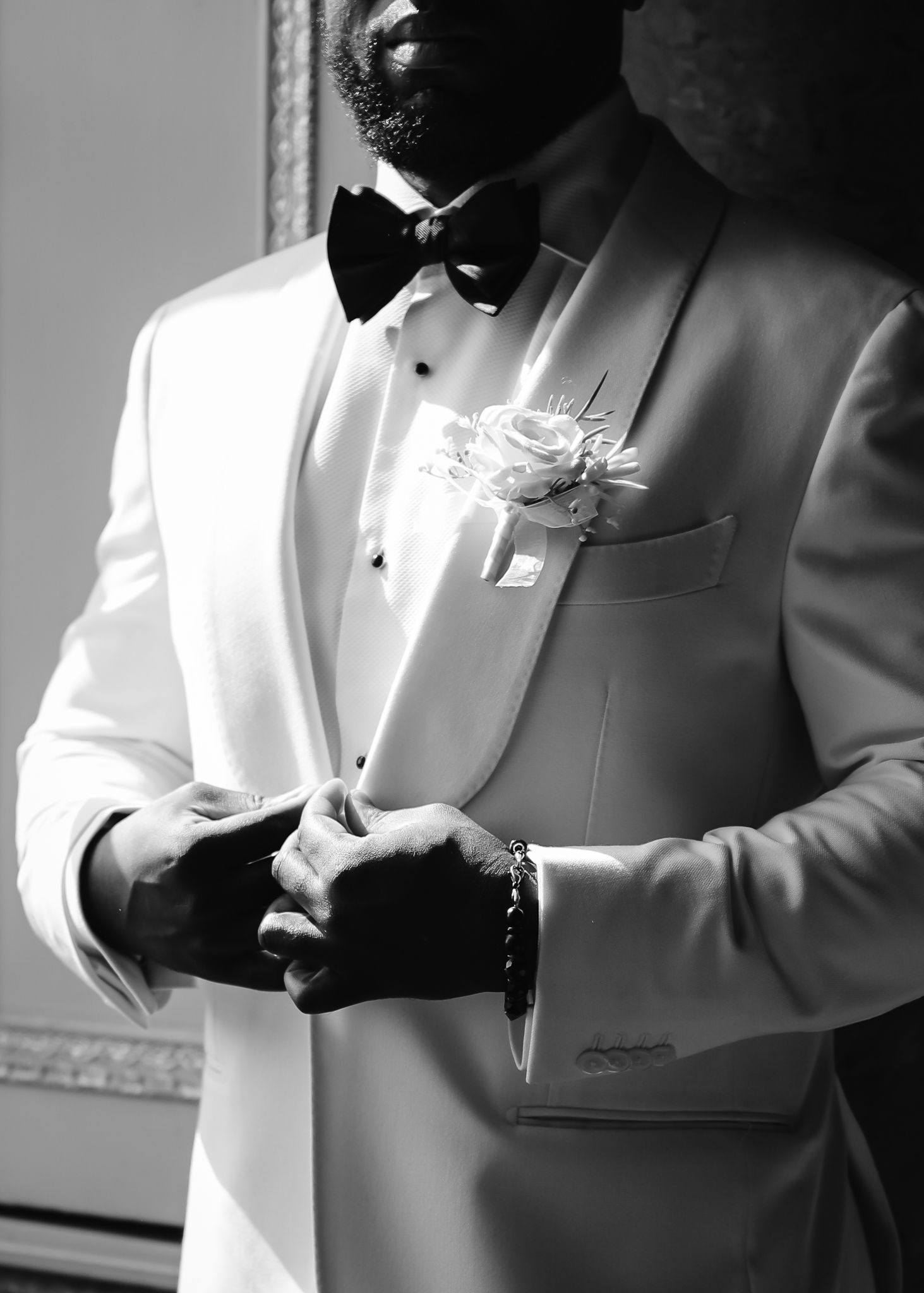Elegant white tuxedo jacket with black bow tie and boutonniere flower in pocket square, shown in black and white.
