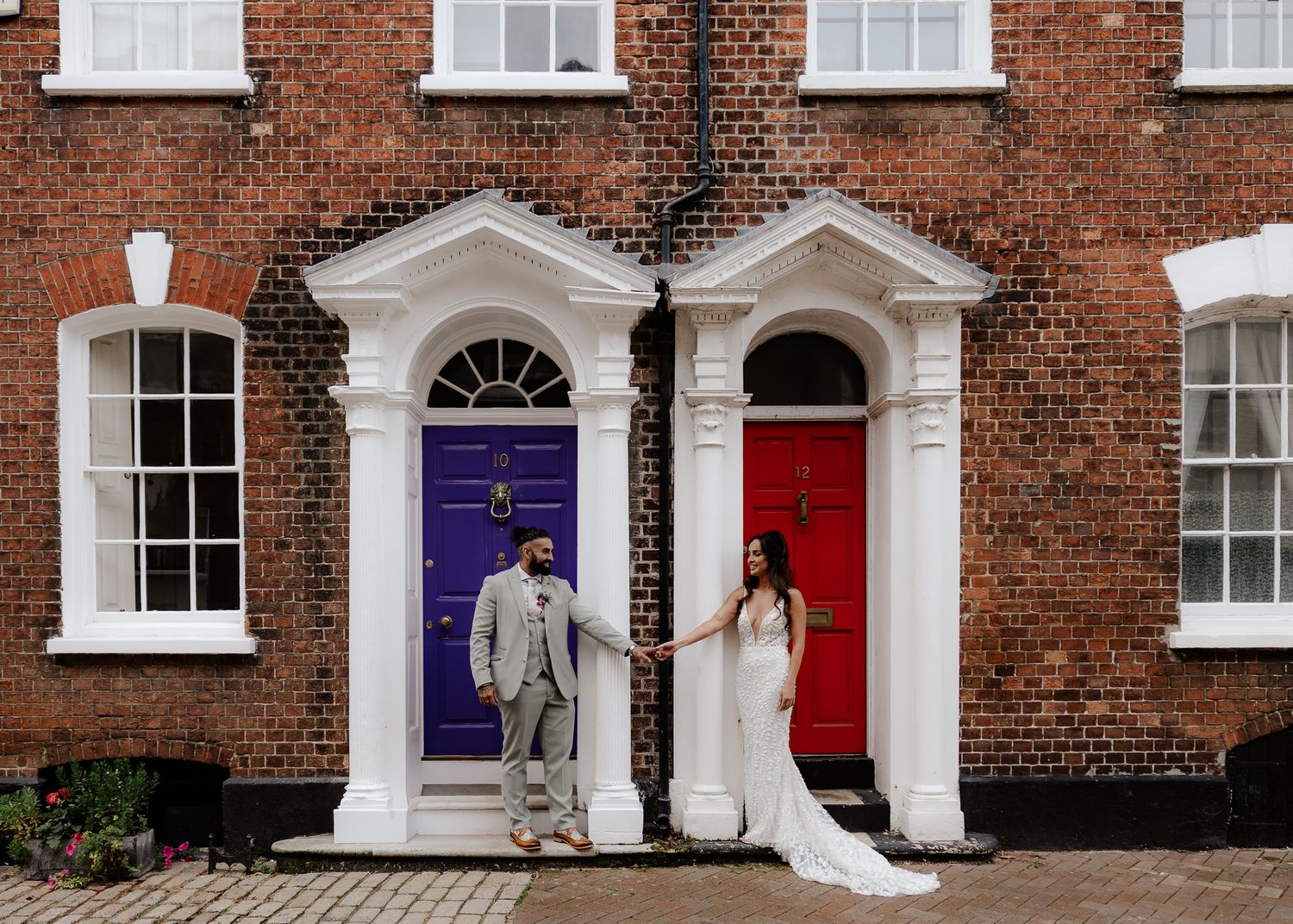 Exterior view of a traditional English brick building with white-trimmed windows and ornate doorways.