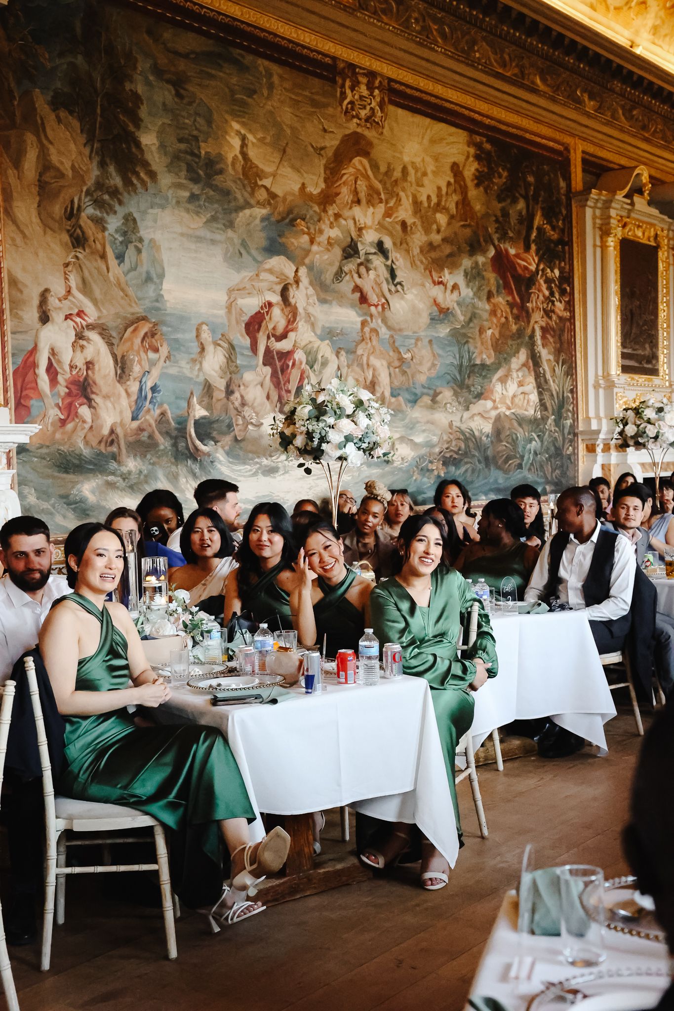 Wedding reception in elegant hall with ornate ceiling murals and guests seated at white-clothed tables.