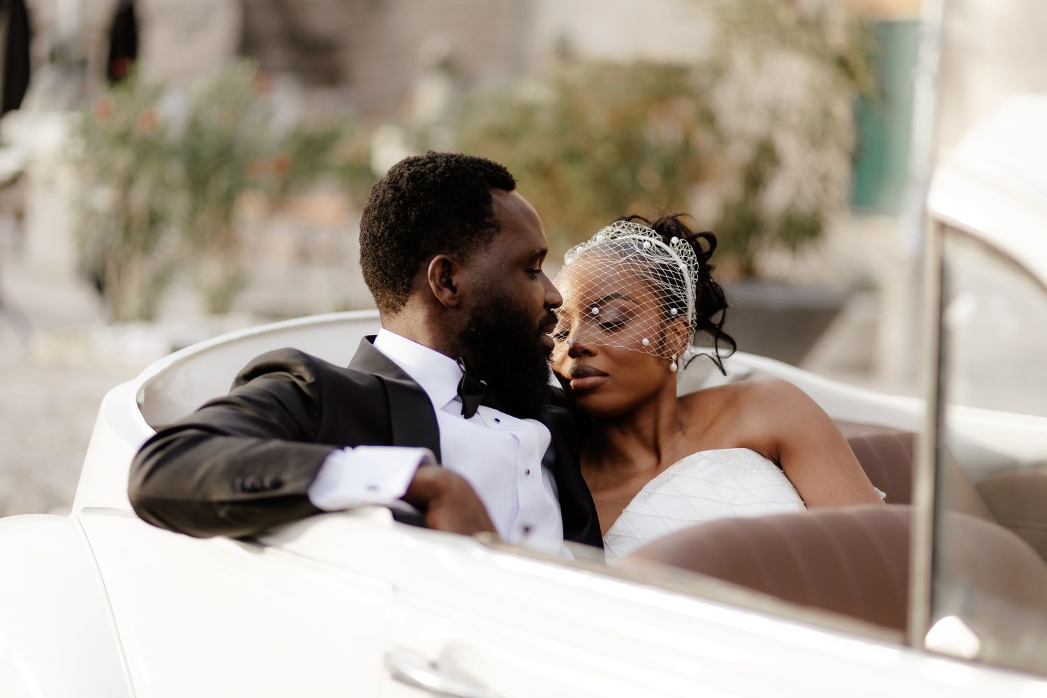 A couple sharing an intimate kiss during their wedding ceremony while guests watch in the background.