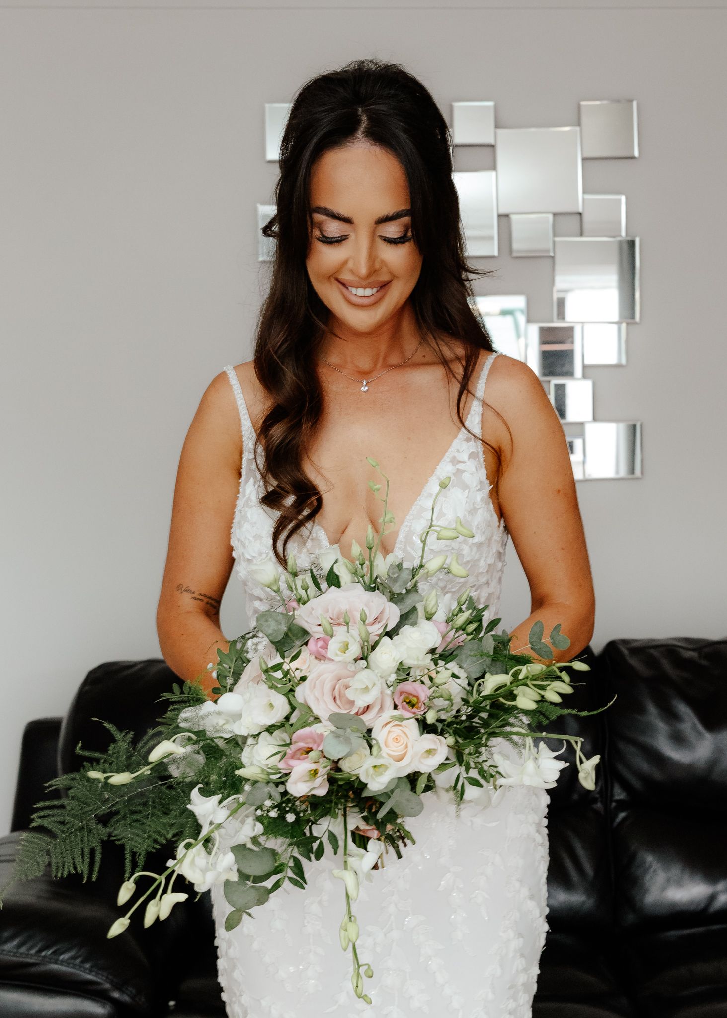 Bride in a white beaded wedding dress holds a cascading bouquet of white and pink flowers with eucalyptus greenery.