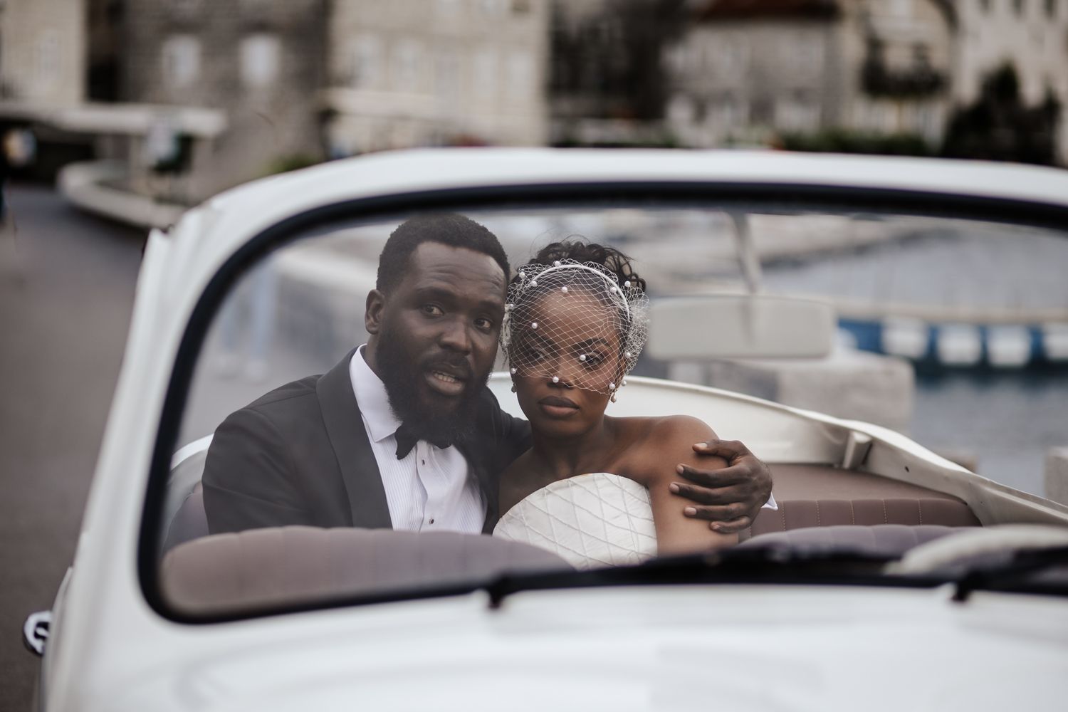 Wedding party rides in style through city streets in classic vintage cars.