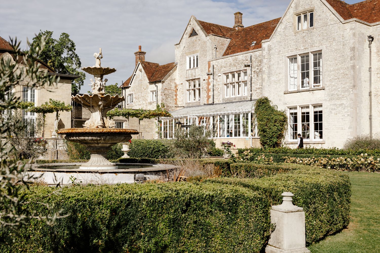 Exterior view of an elegant white stone manor house with manicured gardens.