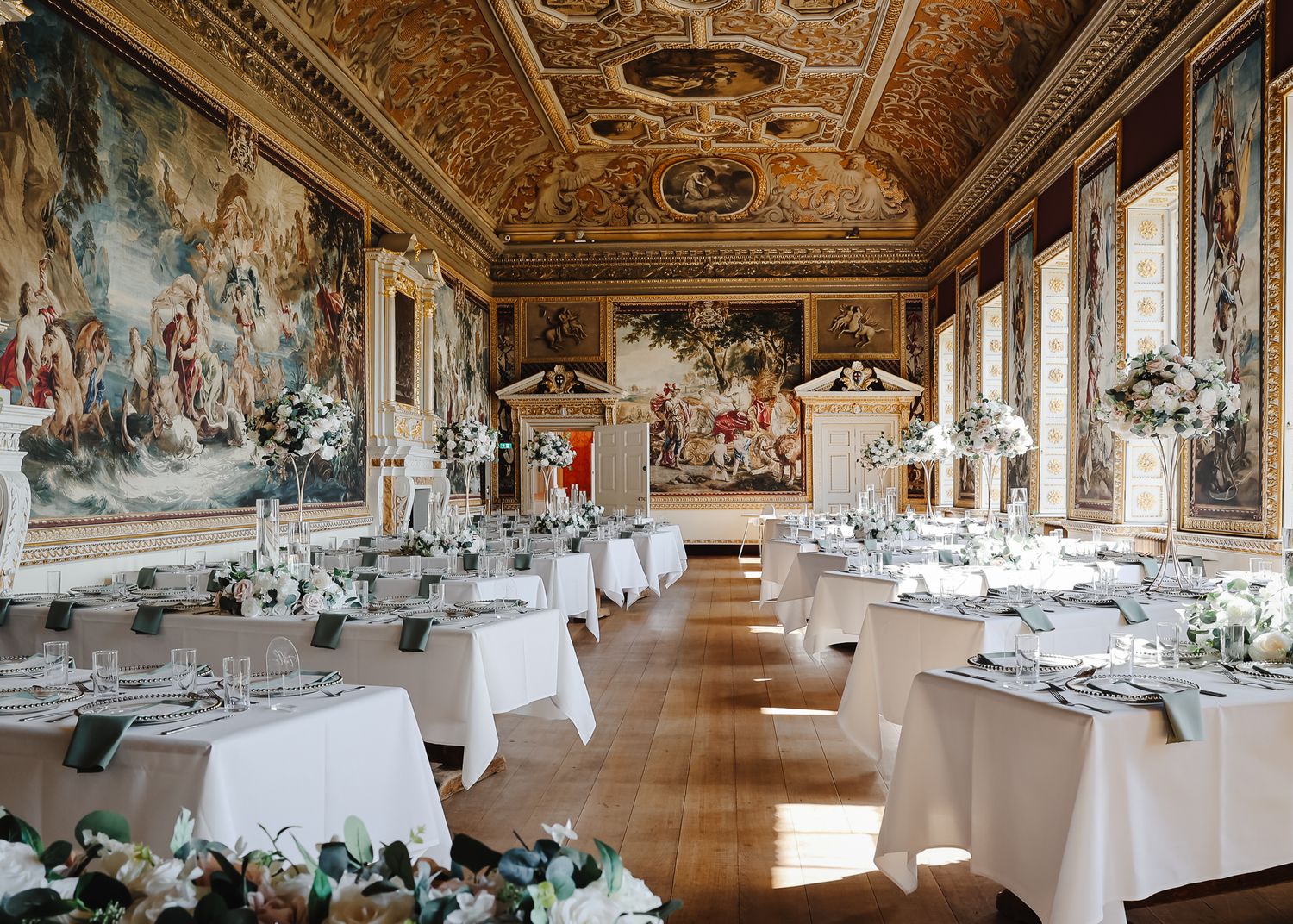 Elegant banquet hall with ornate ceiling frescoes and white-clothed tables set for a formal dining event.