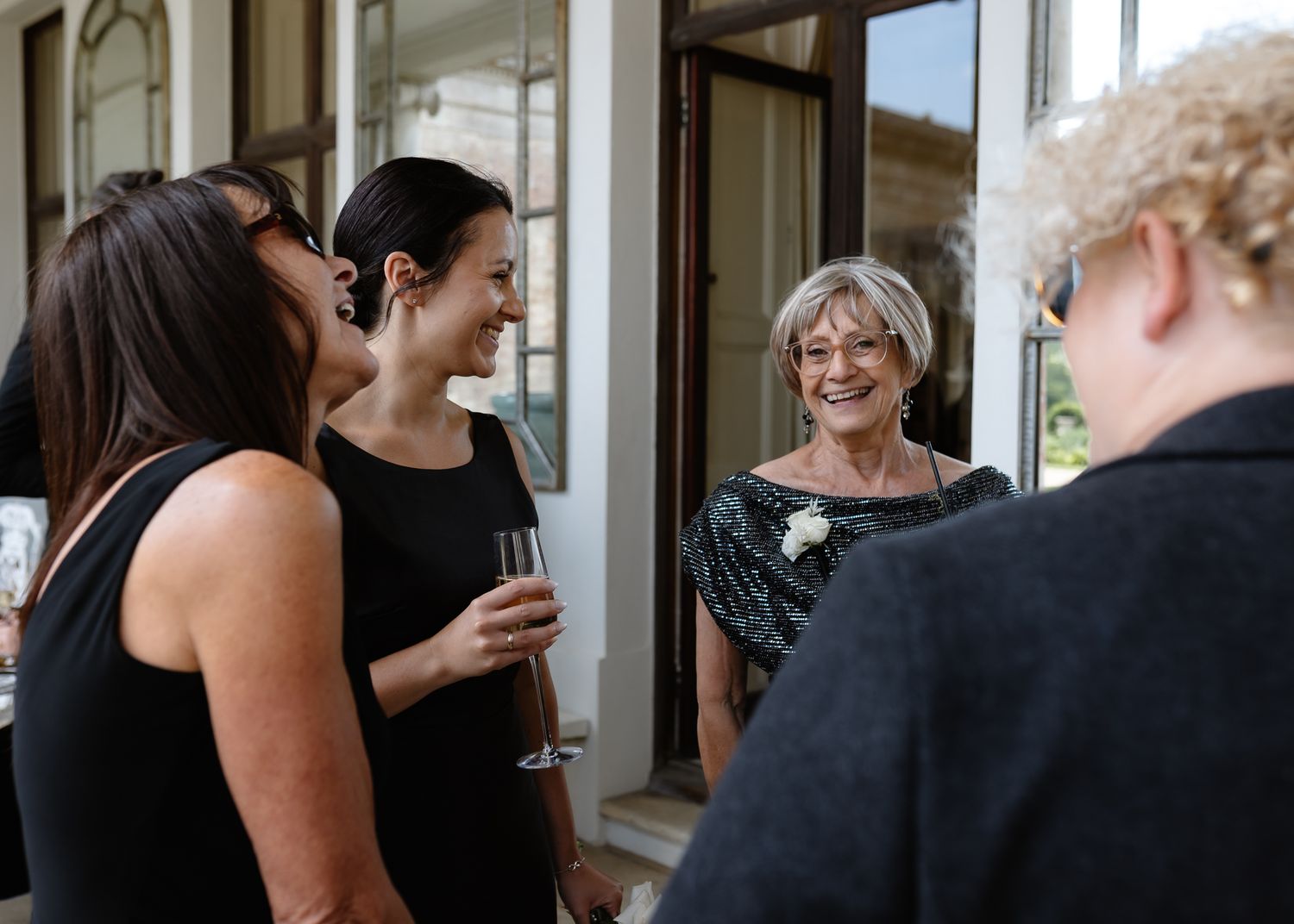 Guests in formal attire gather indoors for wedding celebration.